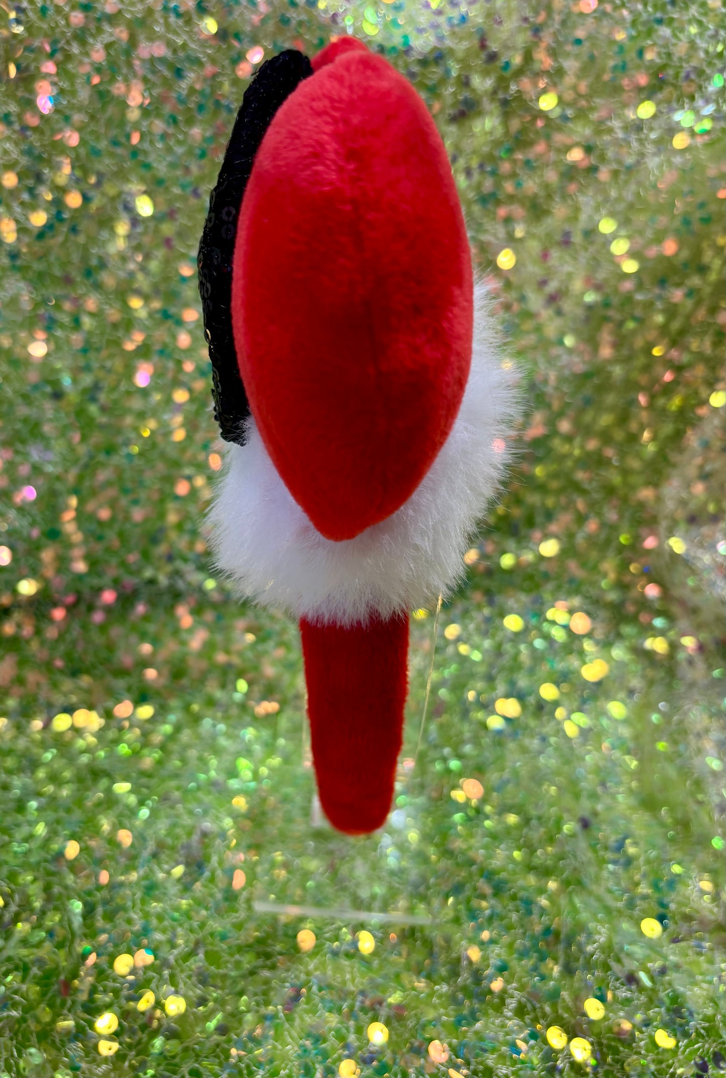 Minnie Mouse ears headband with red plush ears and black bow with gold middle and fluffy white trim on a white background