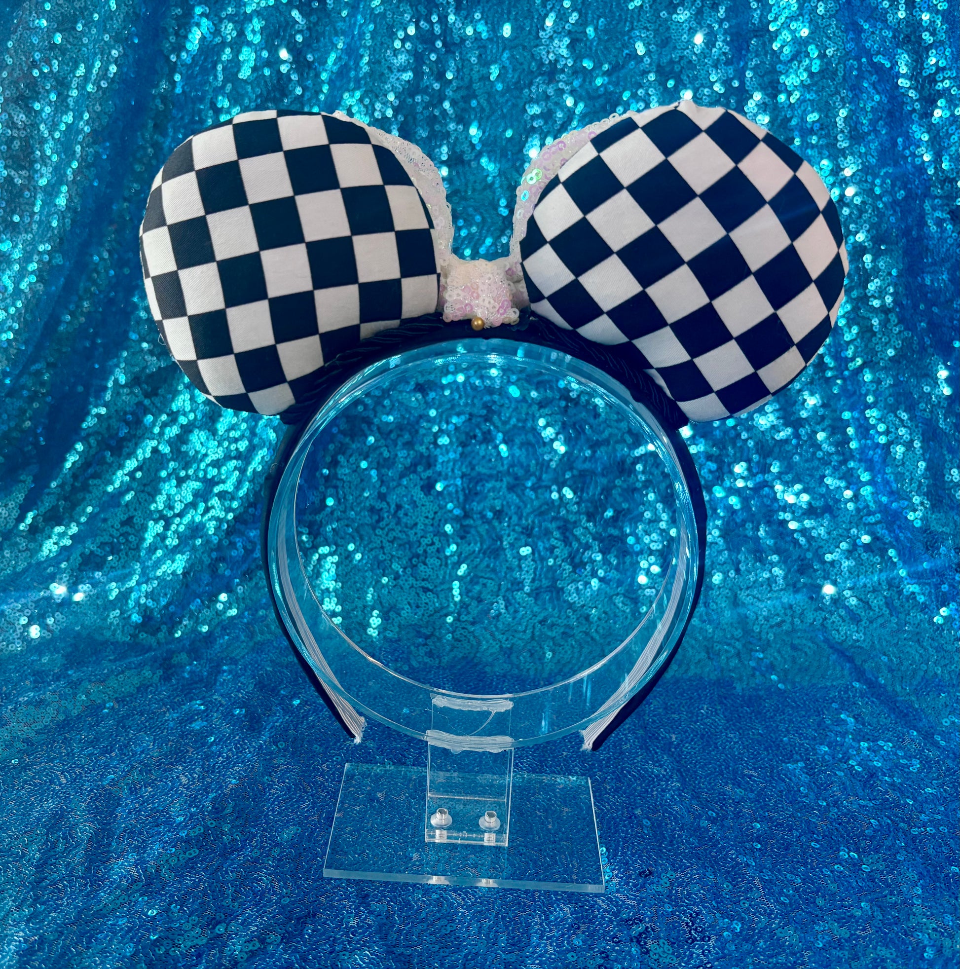 Checkered handmade mouse ears on a black universal headband, shown on a blue background. Back view of set.