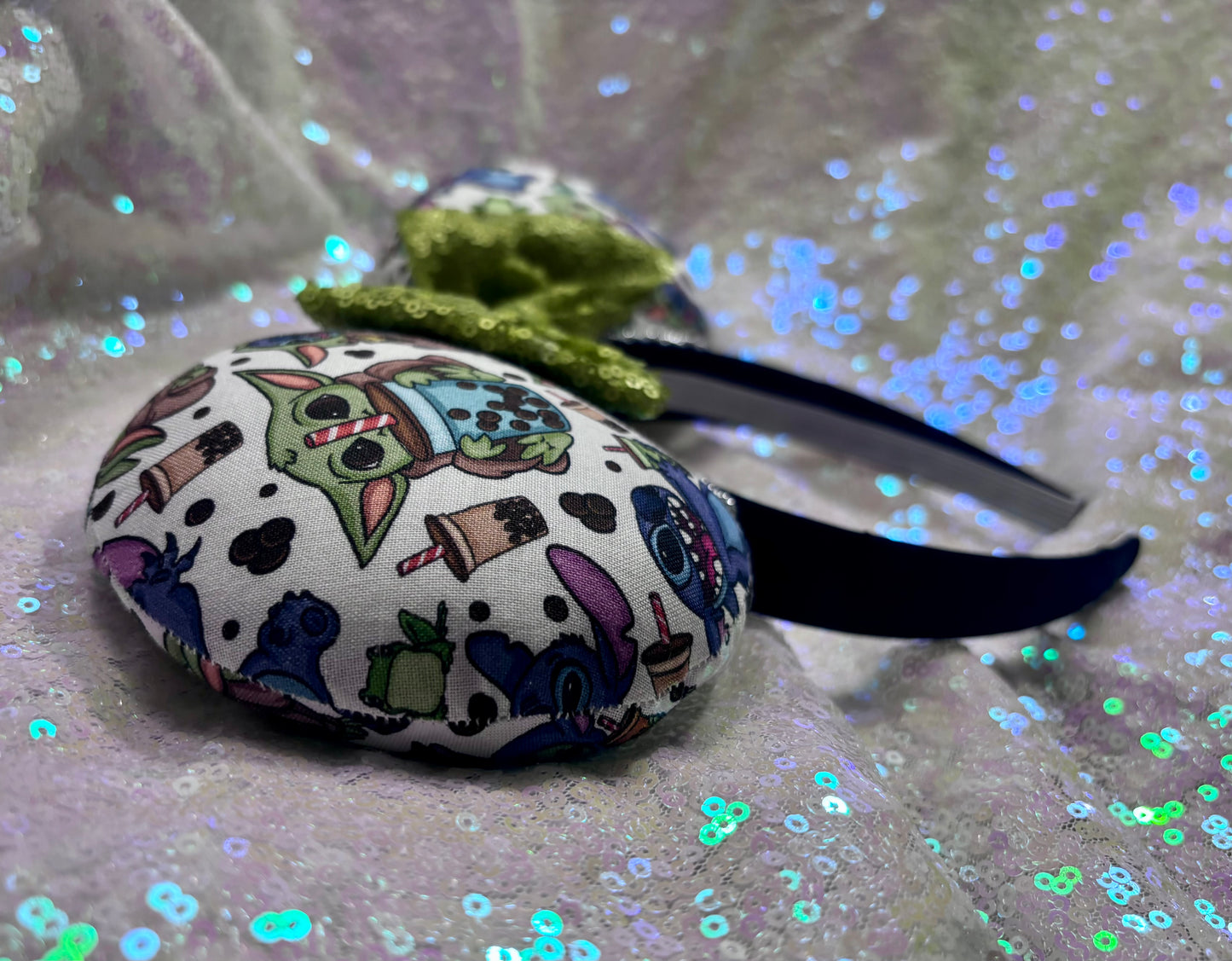 Handmade and ready to ship. Stitch and Baby Yoda are drinking coffee on the front and back with a lime green sequin bow. Shown on a white background.