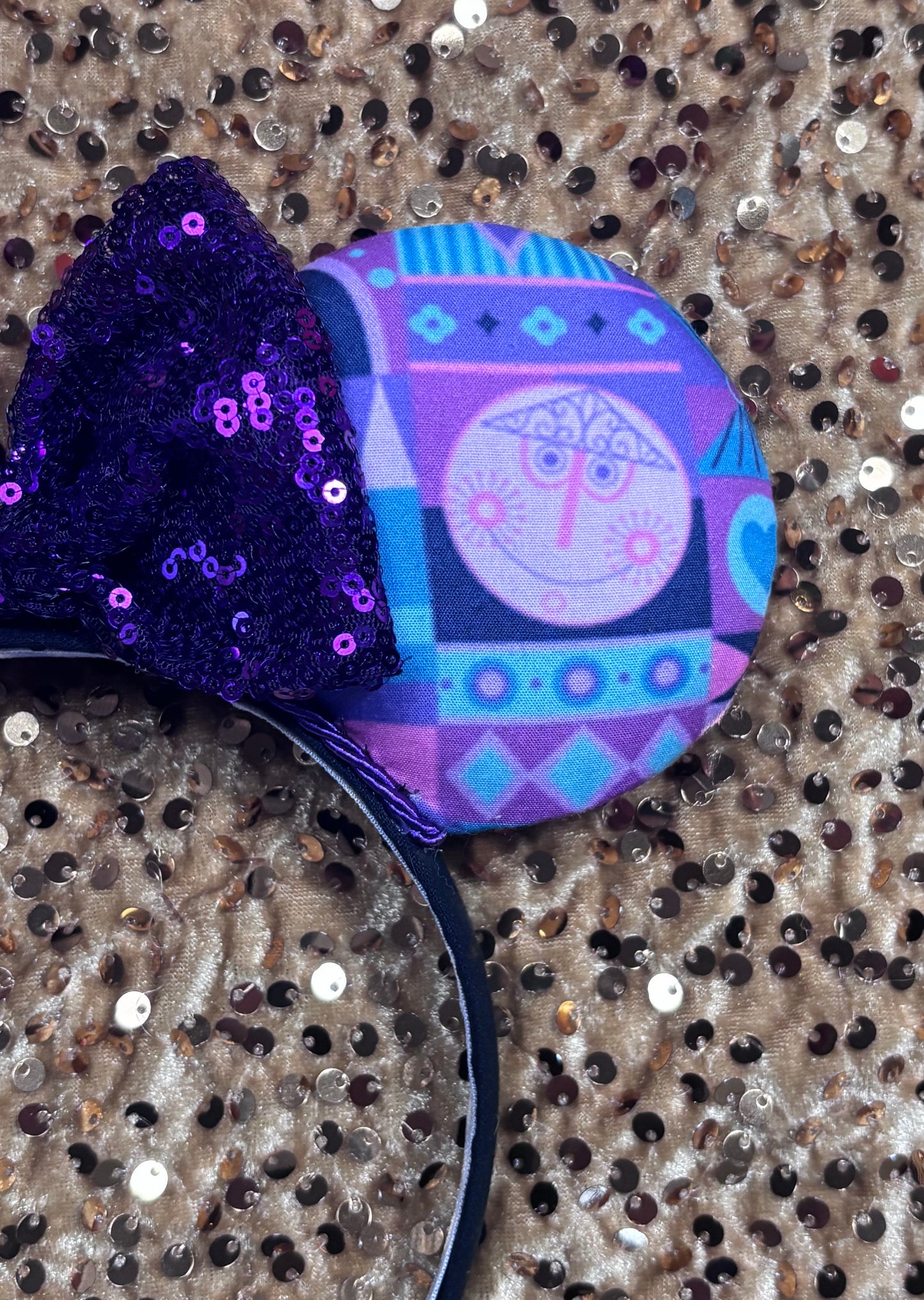 Decorative headband with purple sequins and colorful pattern on a textured background