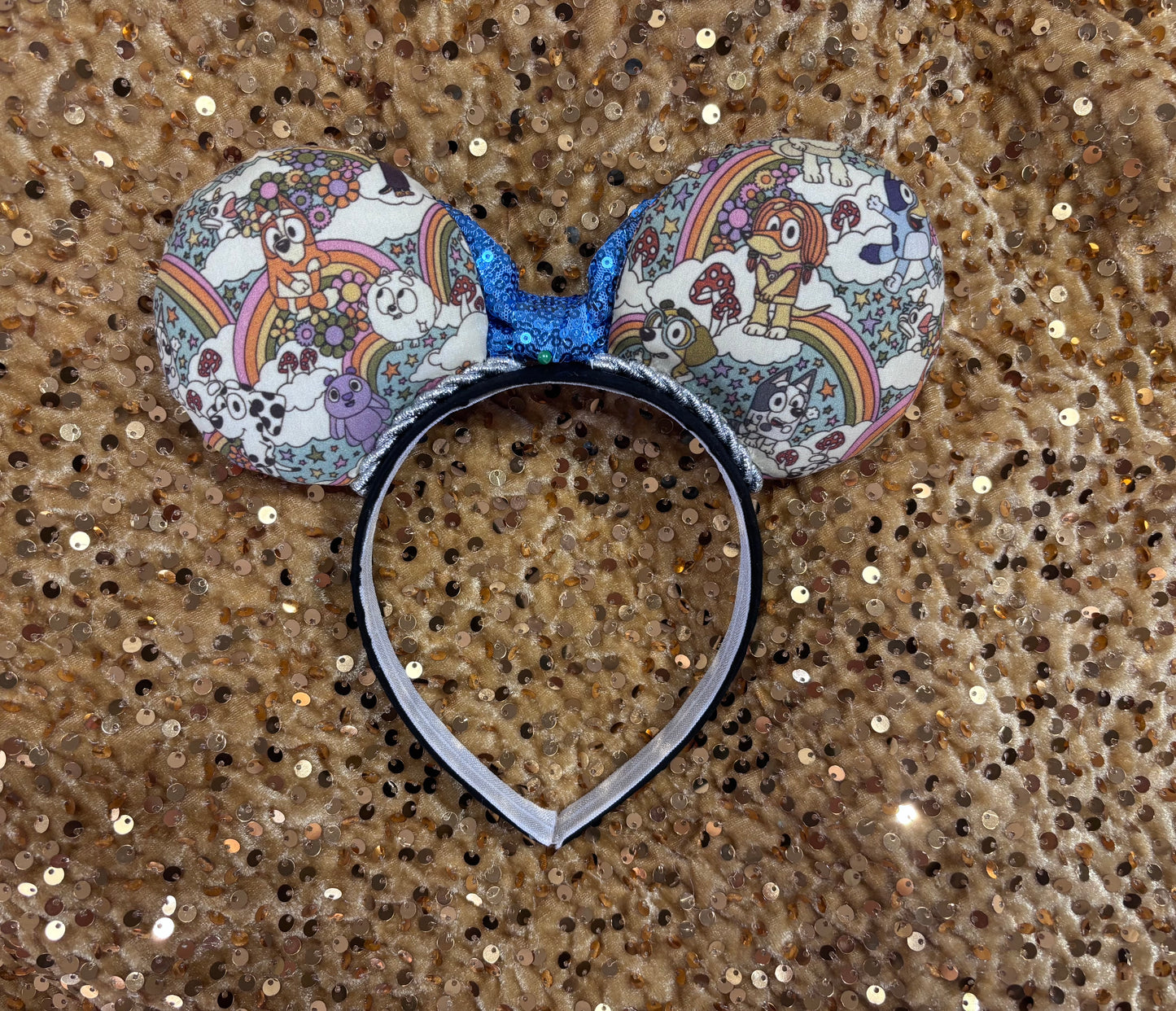 Mouse ears with a blue bow and colorful floral pattern with Bluey and friends on a white background