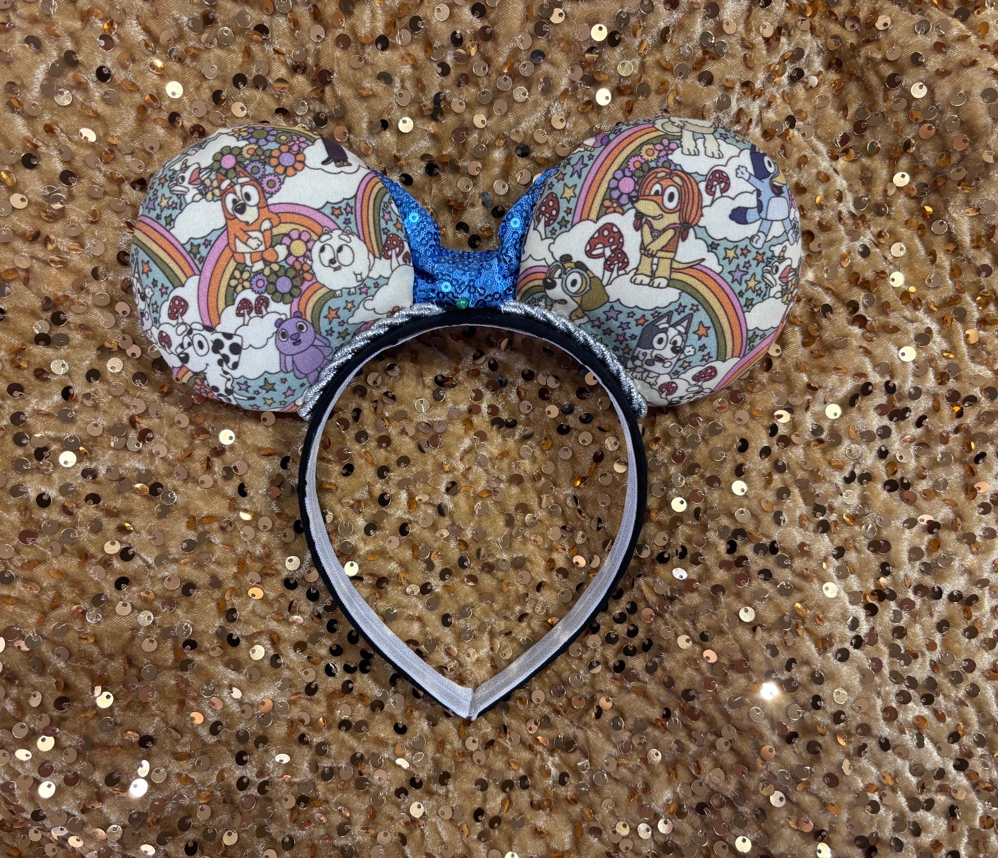 Mouse ears with a blue bow and colorful floral pattern with Bluey and friends on a white background