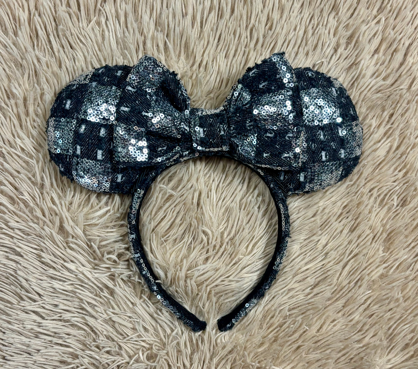A black and silver checkered sequined headband with large bow ears.