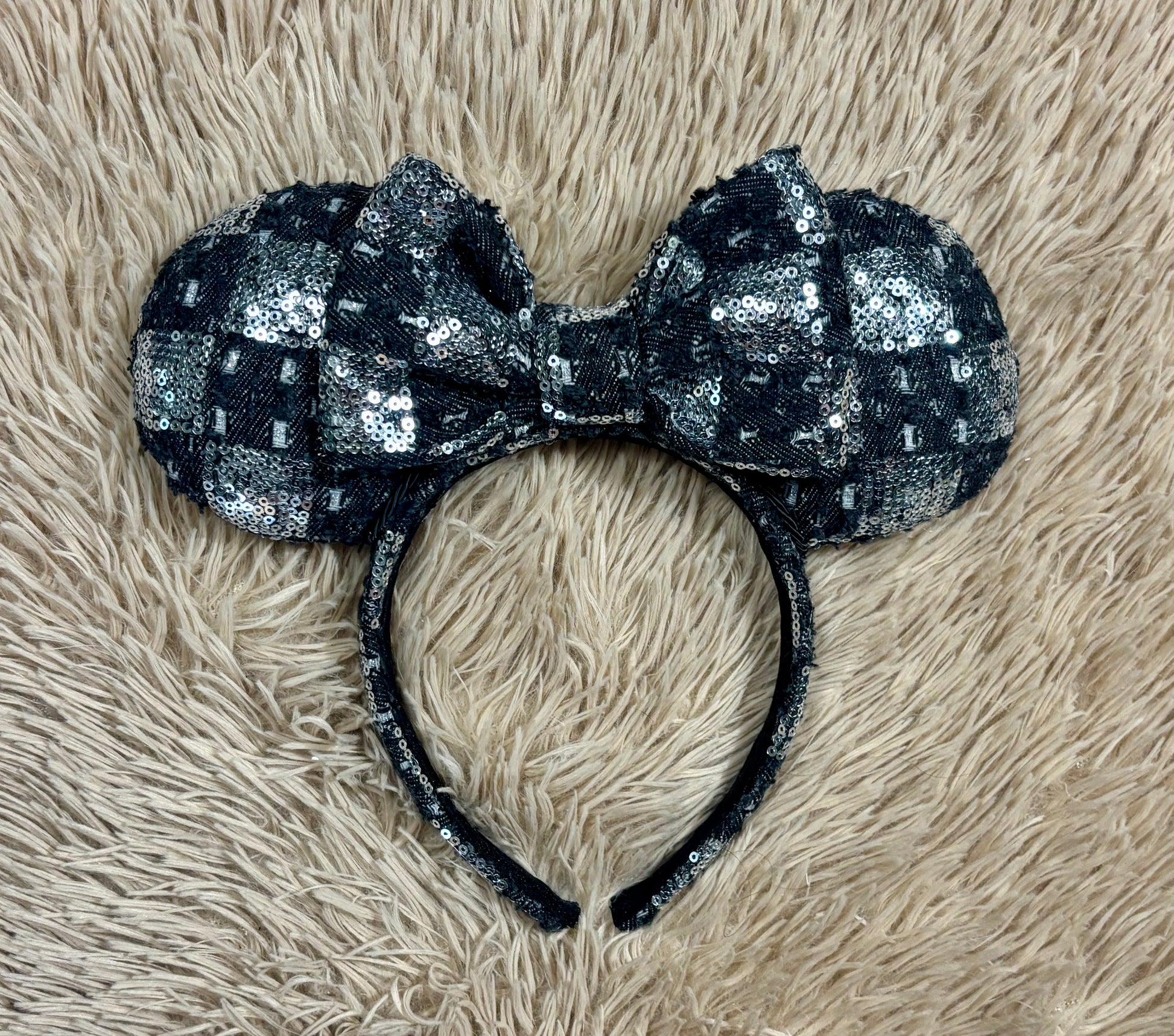A black and silver checkered sequined headband with large bow ears.
