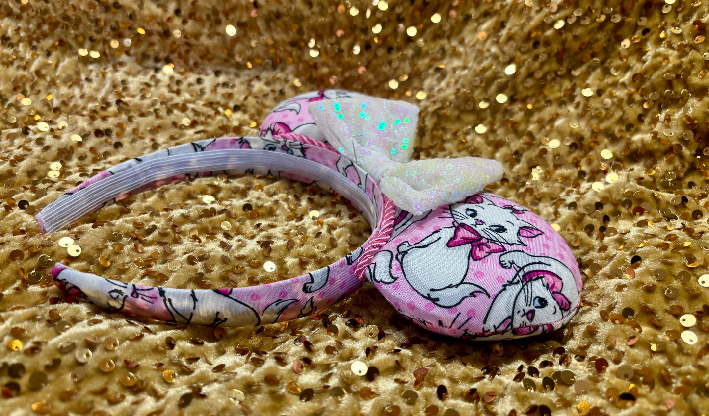 Pink mouse ear headband with white bow shown on a gold glitter background
