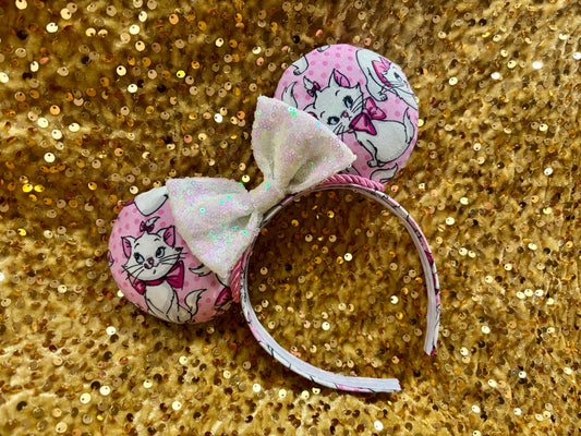 Pink mouse ear headband with white bow shown on a gold glitter background