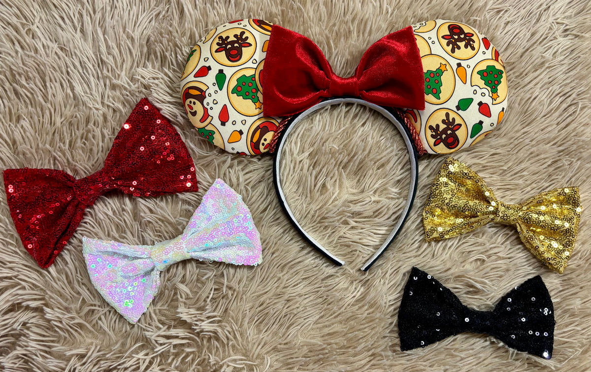 An ear headband featuring a festive Christmas print with red velvet bows, displayed on a beige faux fur background. Various bow options to choose from if you don't want the red plush bow attached.