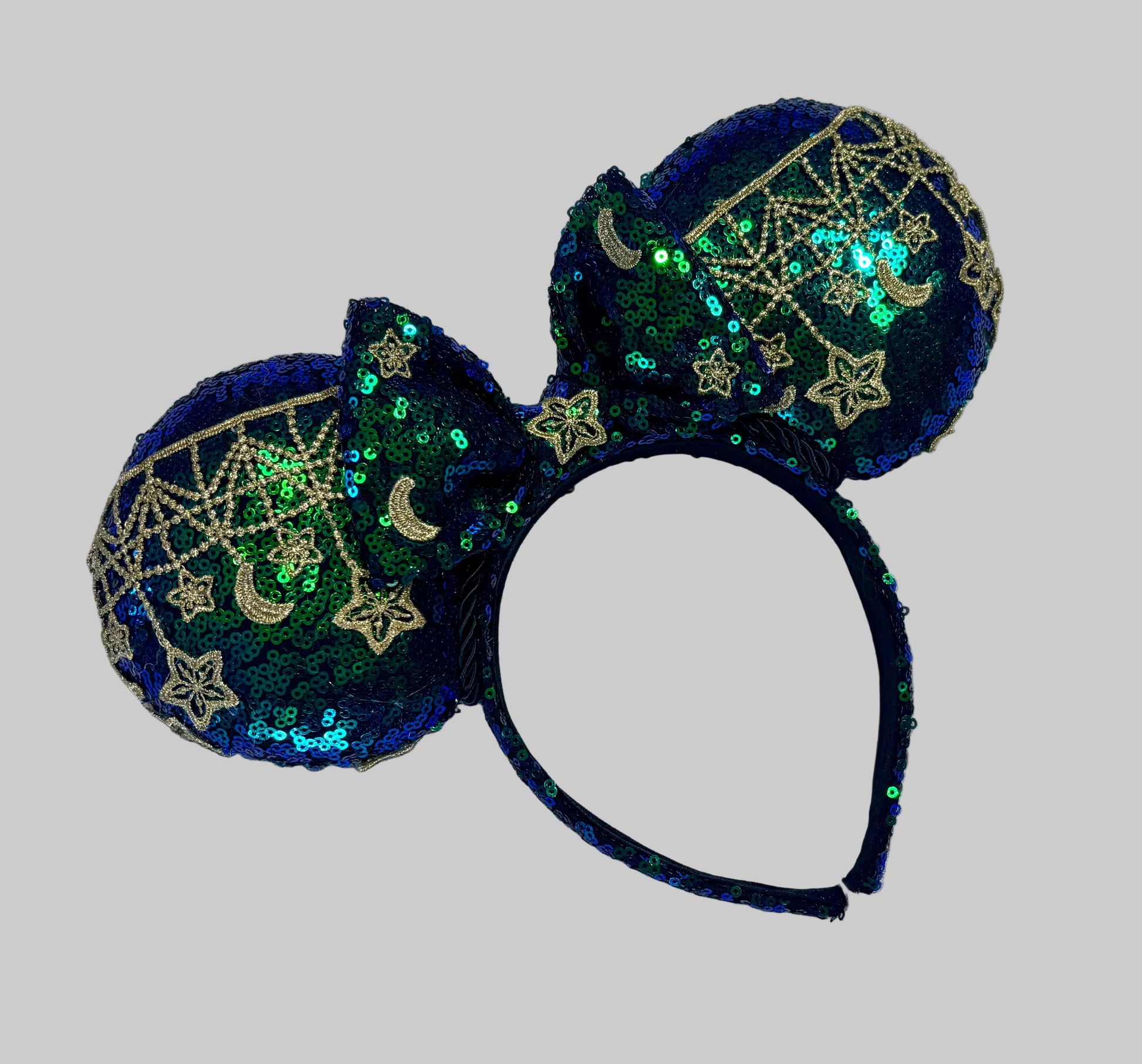 Mouse Ear headband that is a Handmade Iridescent blue and green sequins with gold sun, moon and stars attached to them. bow with star and moon patterns.