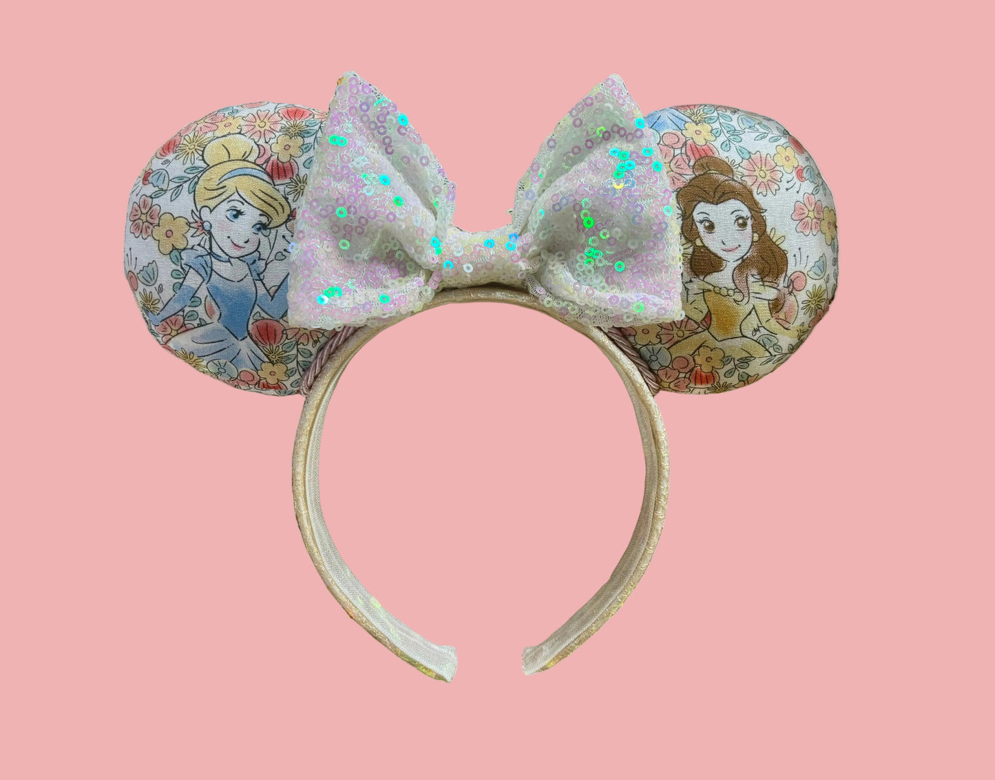Handmade and ready to ship Pretty Princess Mouse ears with Cinderella and Belle shown on the fabric with a white iridescent bow. The headband has a white shimmery fabric and is a universal sized headband.