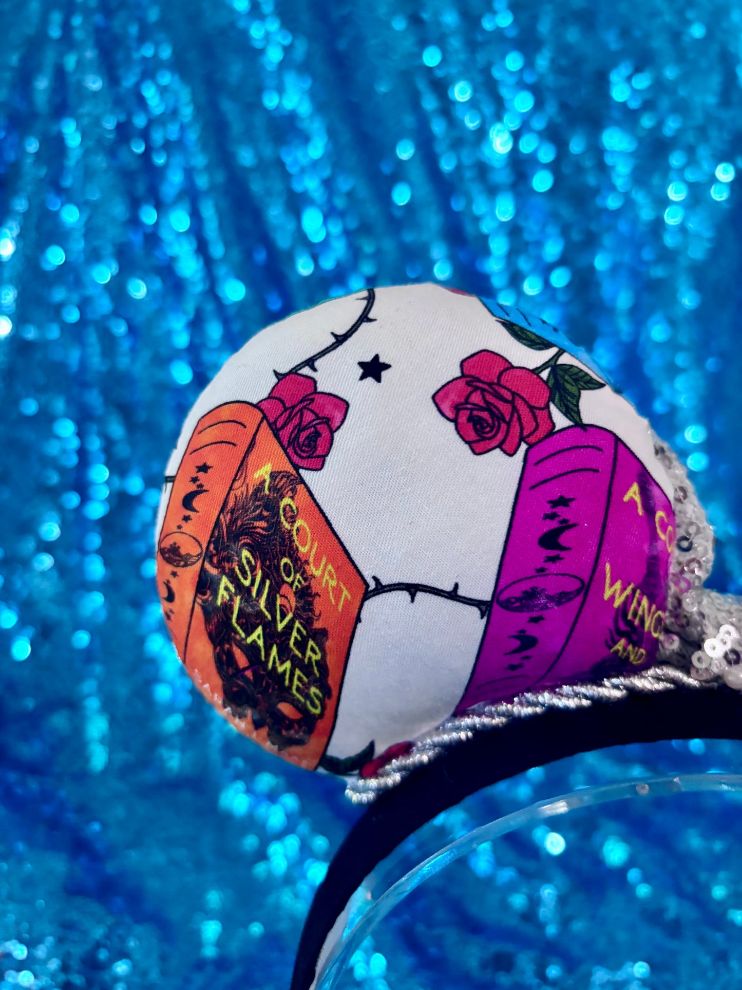Back left ear view with books and roses with thorns on the fabric. 