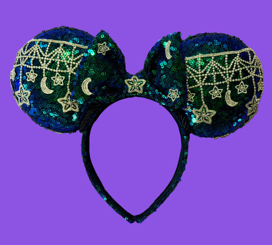 A pair of blue and green iridescent ear headband featuring dark blue and green sequins with gold embroidered stars, moons, and web patterns.