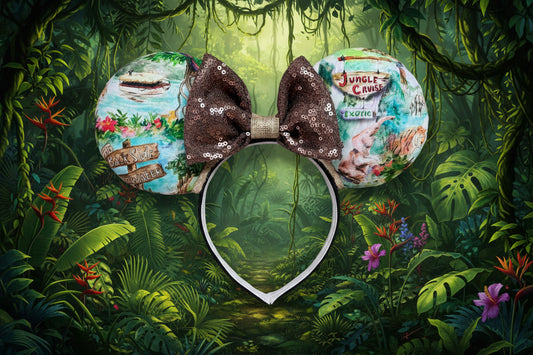 Jungle-themed mouse ears with a brown sequin bow. Shown on a lush green leaf background