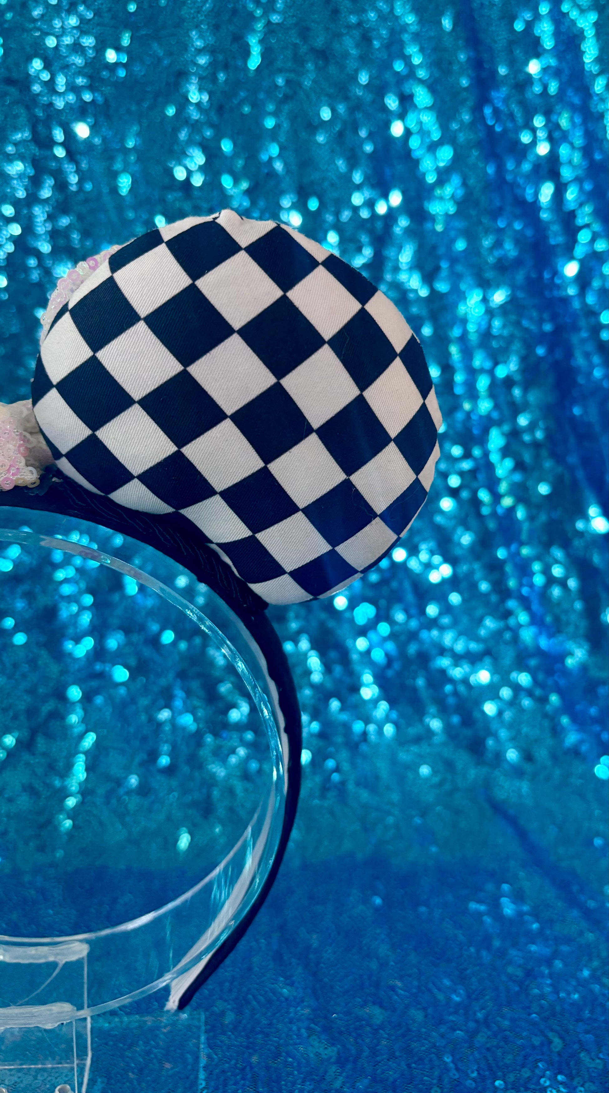 Checkered blue and white mouse ear against a blue glittery background
