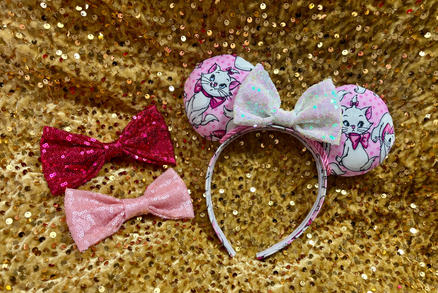 Pink mouse ear headband with white bow shown on a gold glitter background
