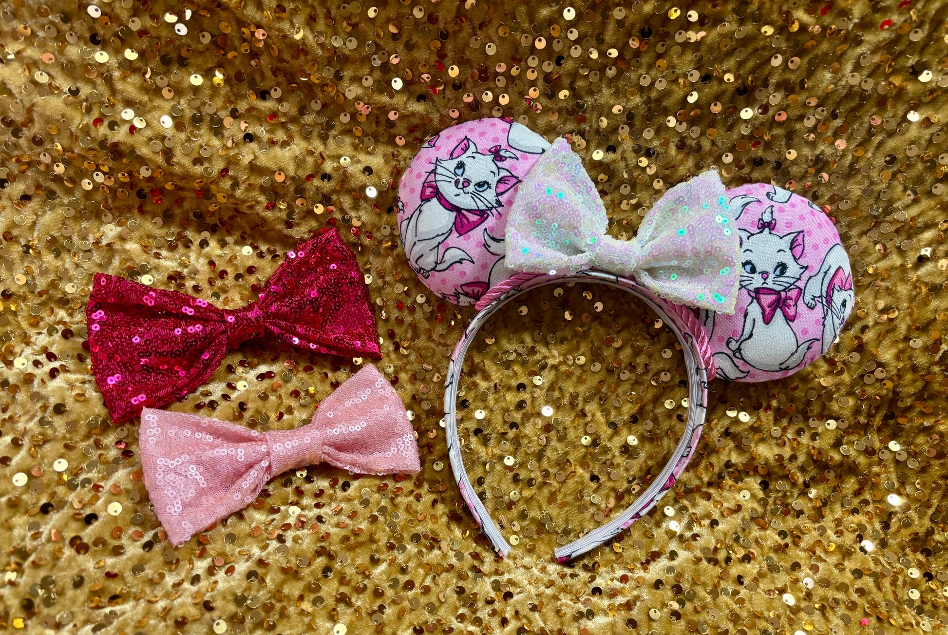 Pink mouse ear headband with white bow shown on a gold glitter background