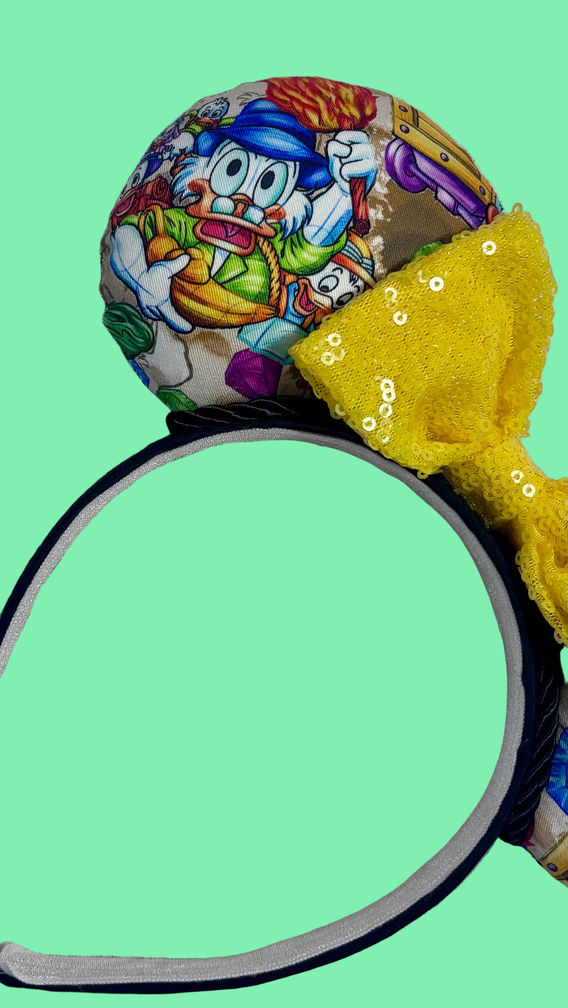 Close up of the left front mouse ear, yellow sequin bow and the headband. 
