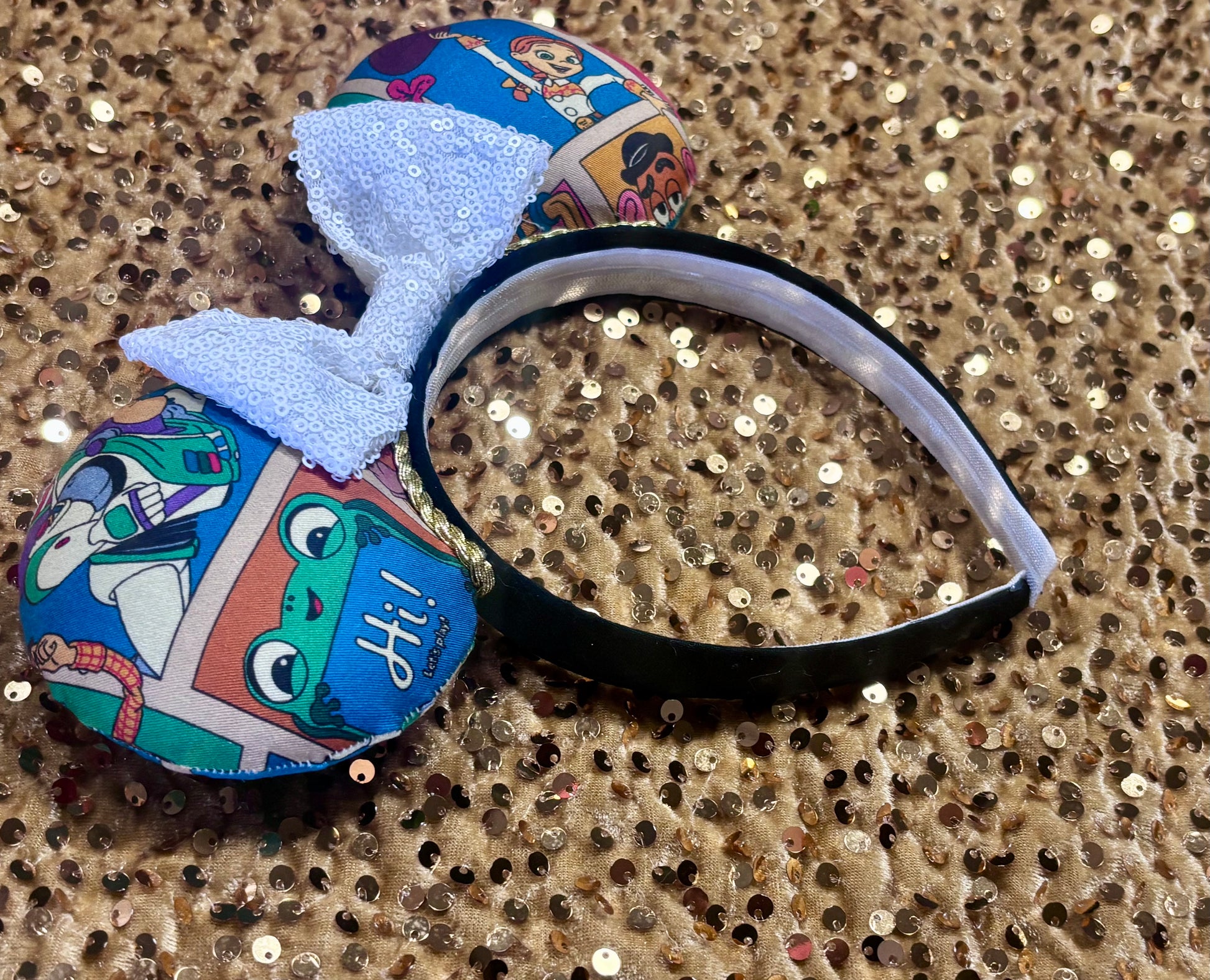 Handmade and ready to ship TS5 Inspired mouse ears. The character fabric is on the front and the back. On a universal sized black poly fabric headband. With a white sequin bow.