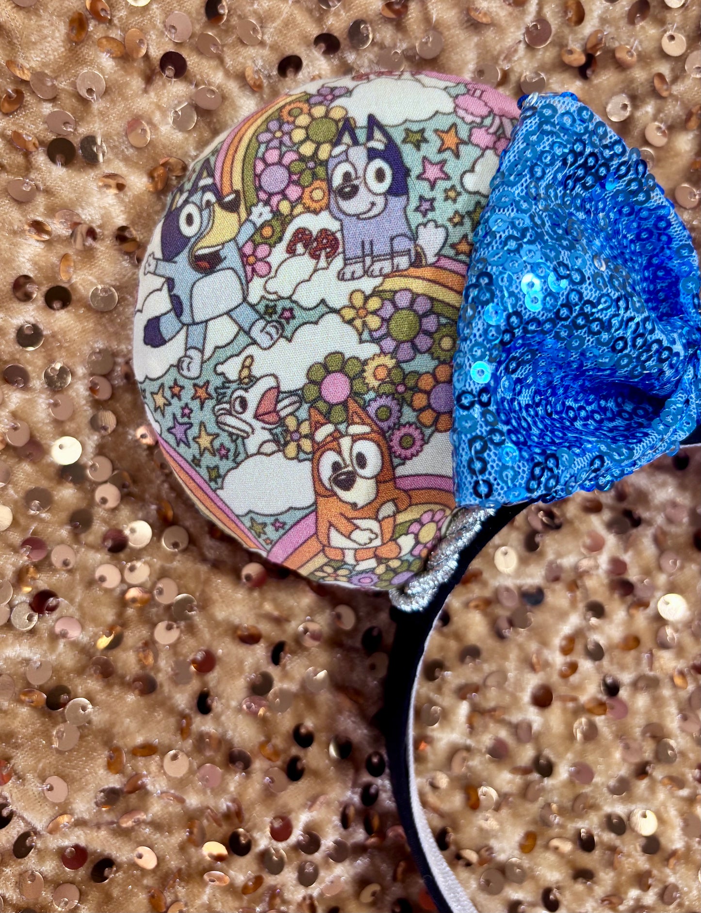 Mouse ears with a blue bow and colorful floral pattern with Bluey and friends on a white background