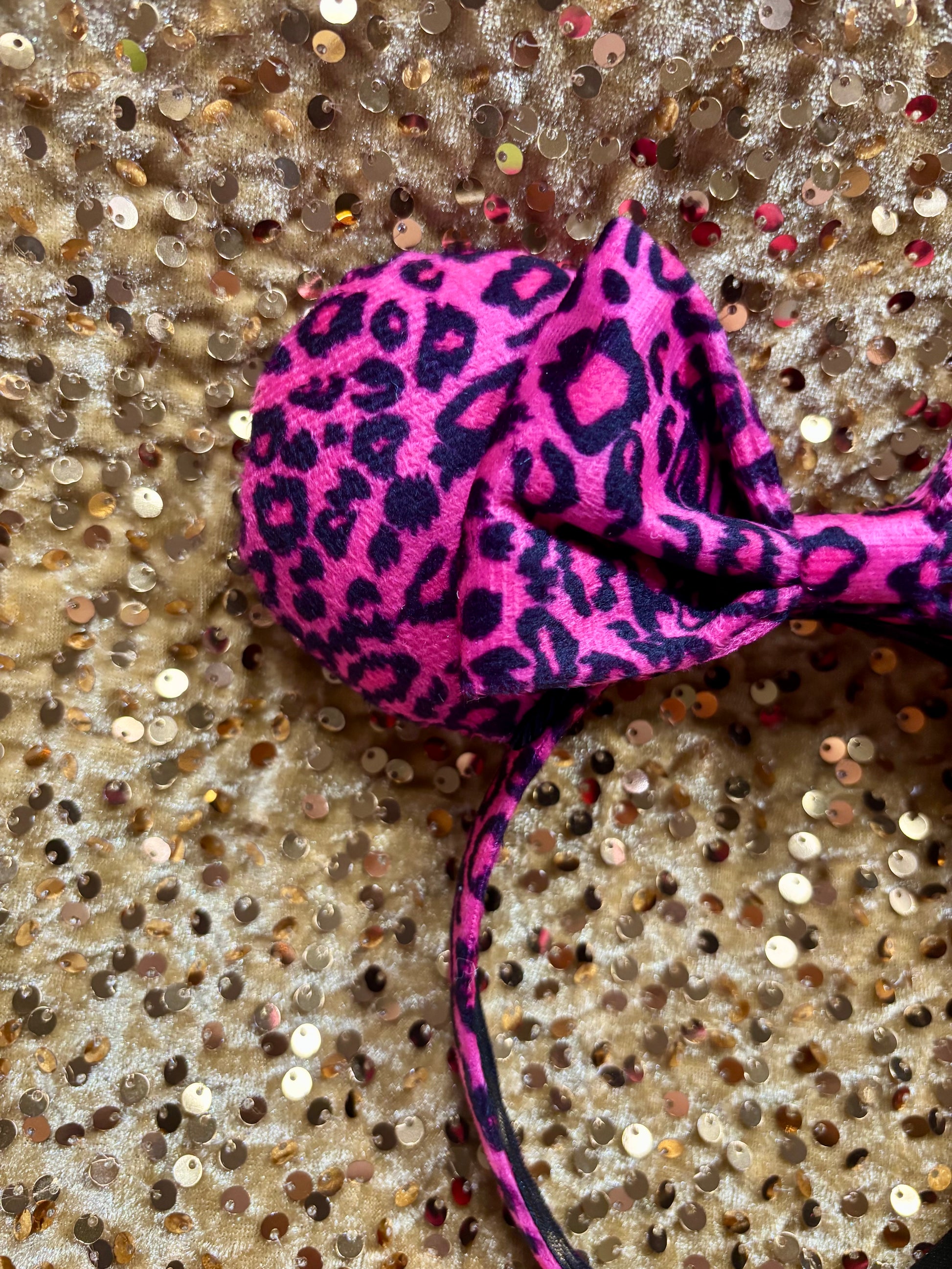 Pink headband with leopard print on a glittery surface
