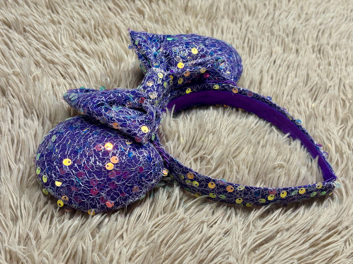 A purple iridescent sequined headband with two large mouse shaped ears.