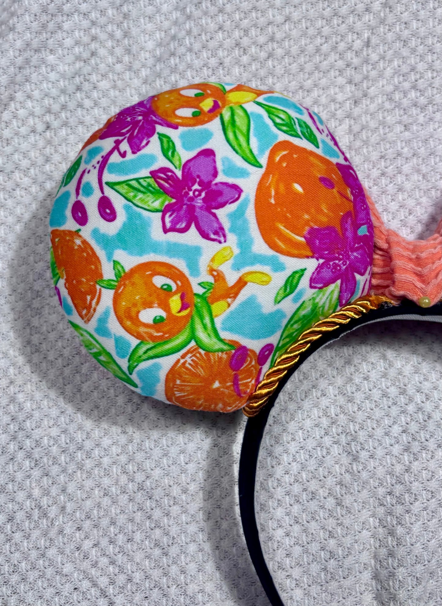 Colorful headband with floral and fruit pattern with an Orange bird on a textured gray background