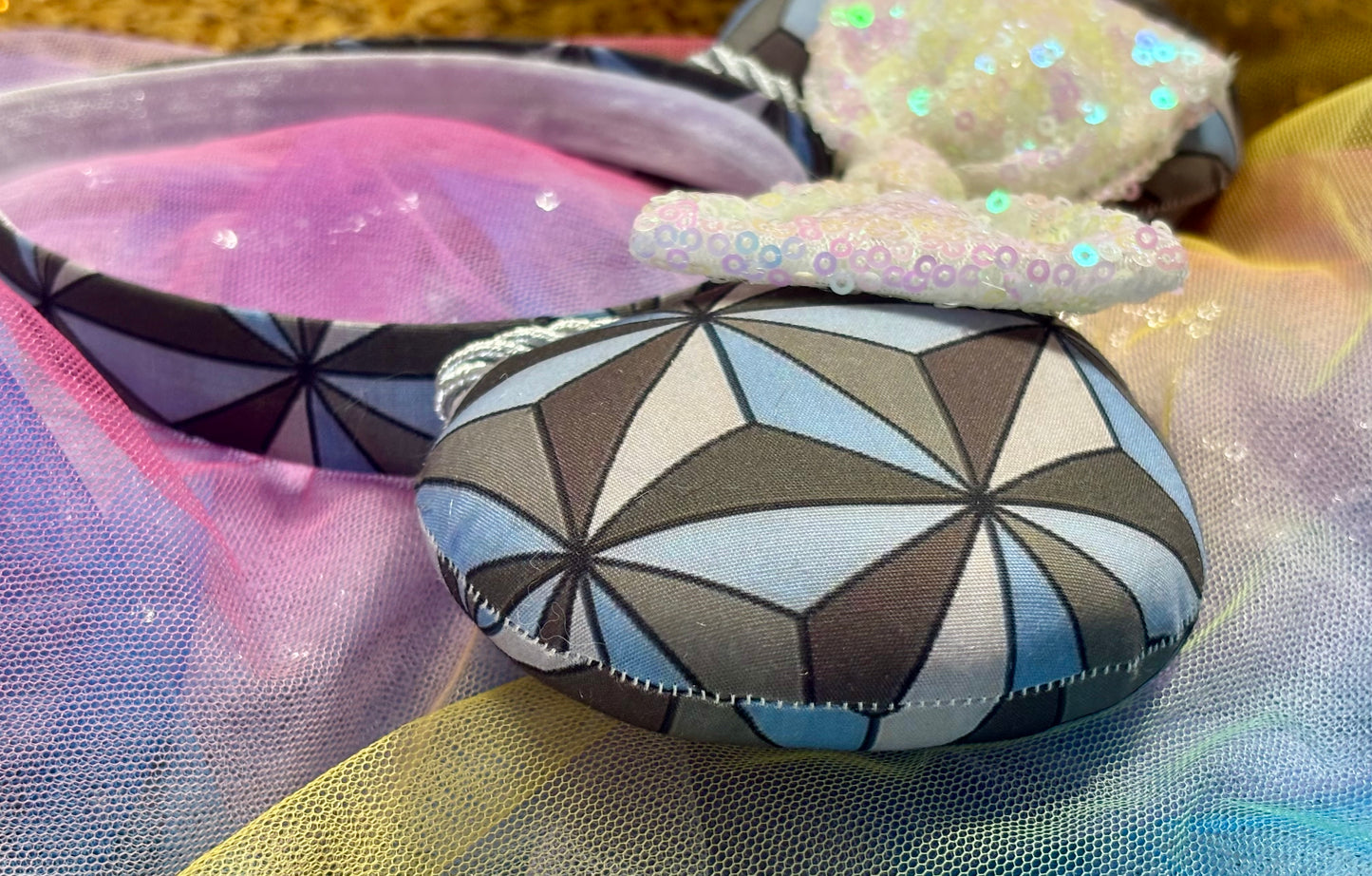 Handmade and ready to ship Mouse ear headband with a geometric design inspired by Spaceship Earth ride and a white iridescent bow on a universal sized black headband.