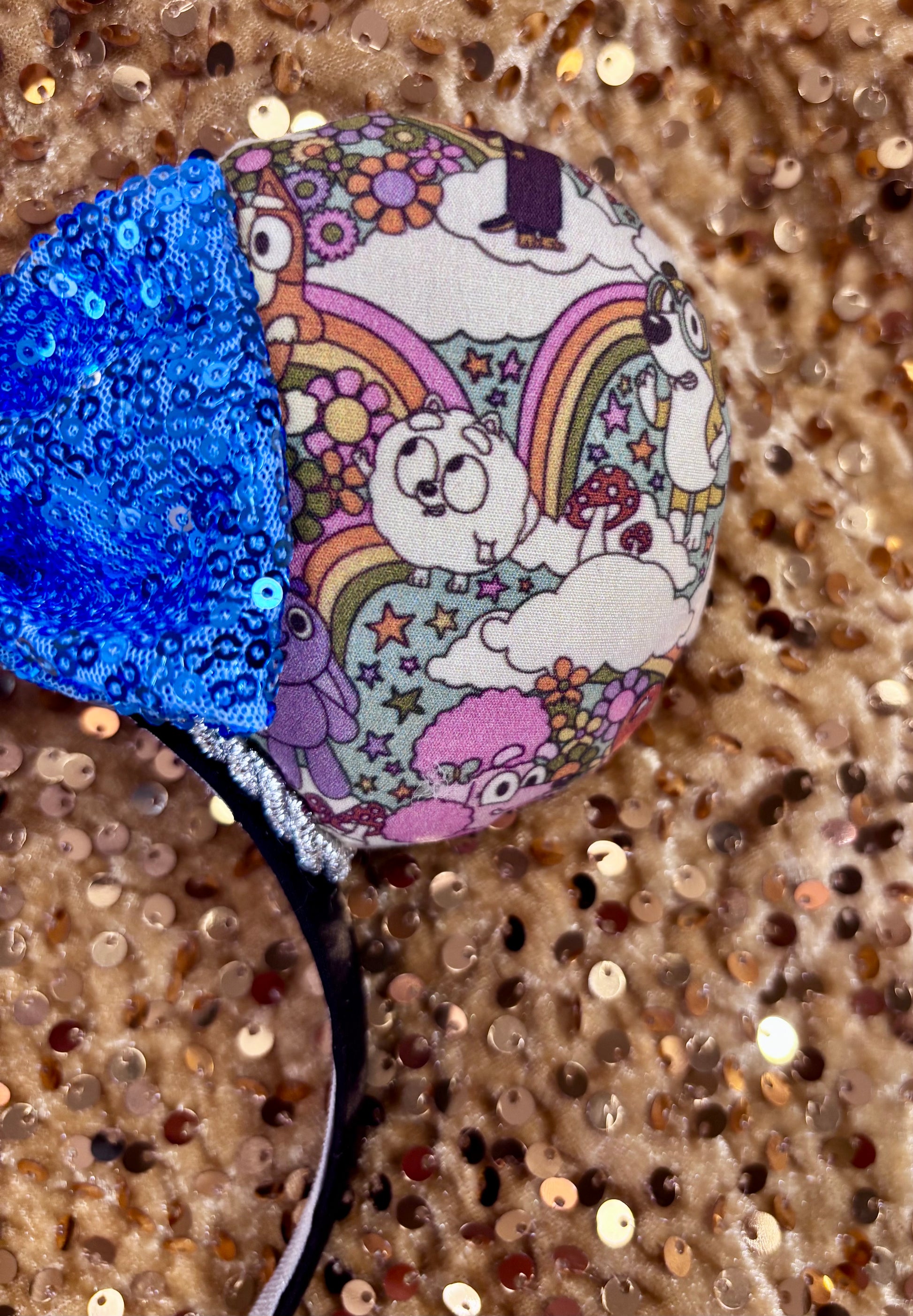 Mouse ears with a blue bow and colorful floral pattern with Bluey and friends on a white background
