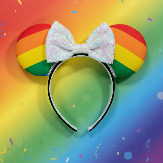 Rainbow-colored mouse ears ona black headband with a white sequin bow. Shown on a colorful gradient background