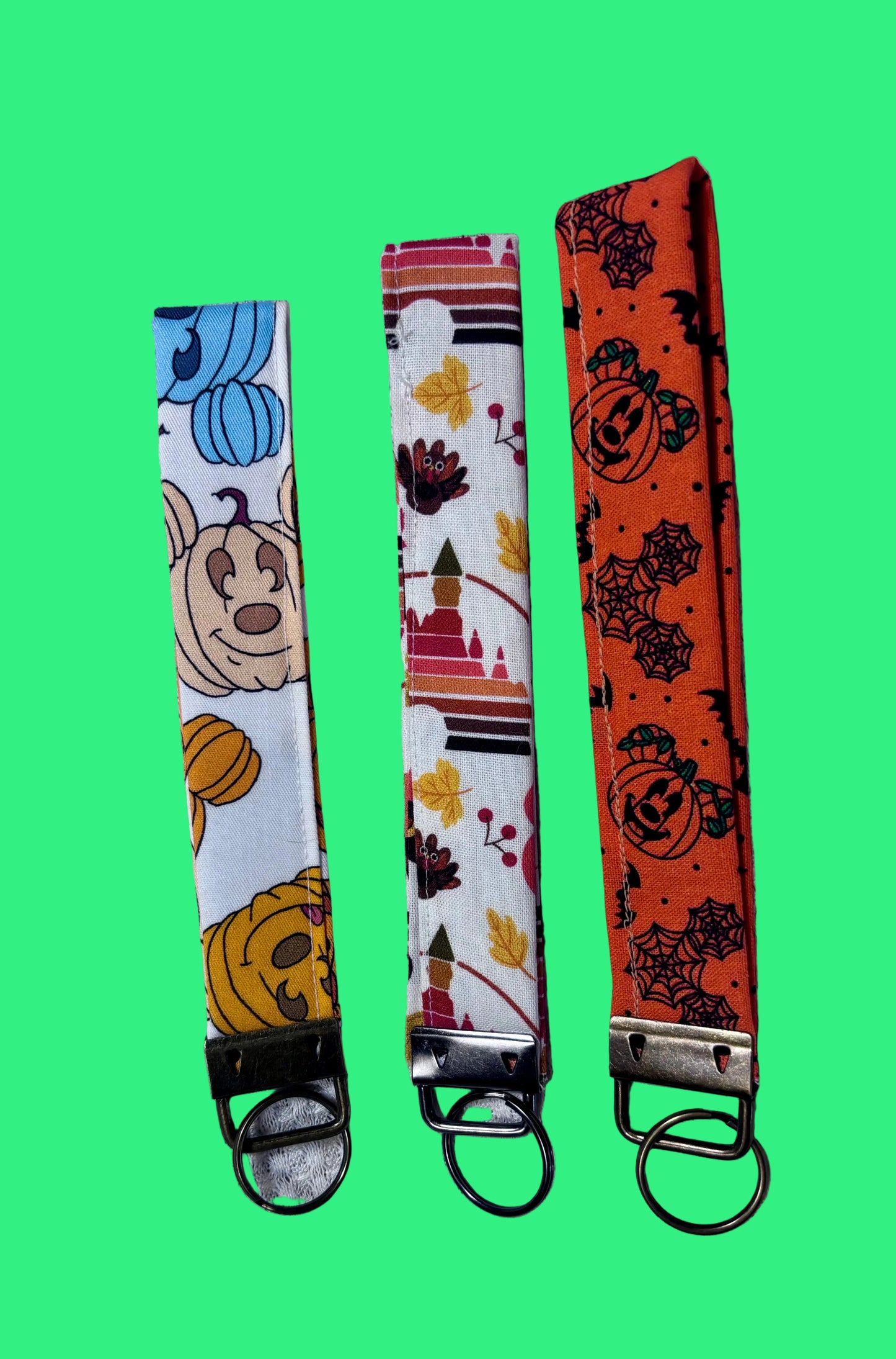 Handmade and ready to ship. Three keychain wristlets with Halloween-themed designs in: Mouse pumpkin, boo to you and thanksgiving fabric designs. Back side of keychains.