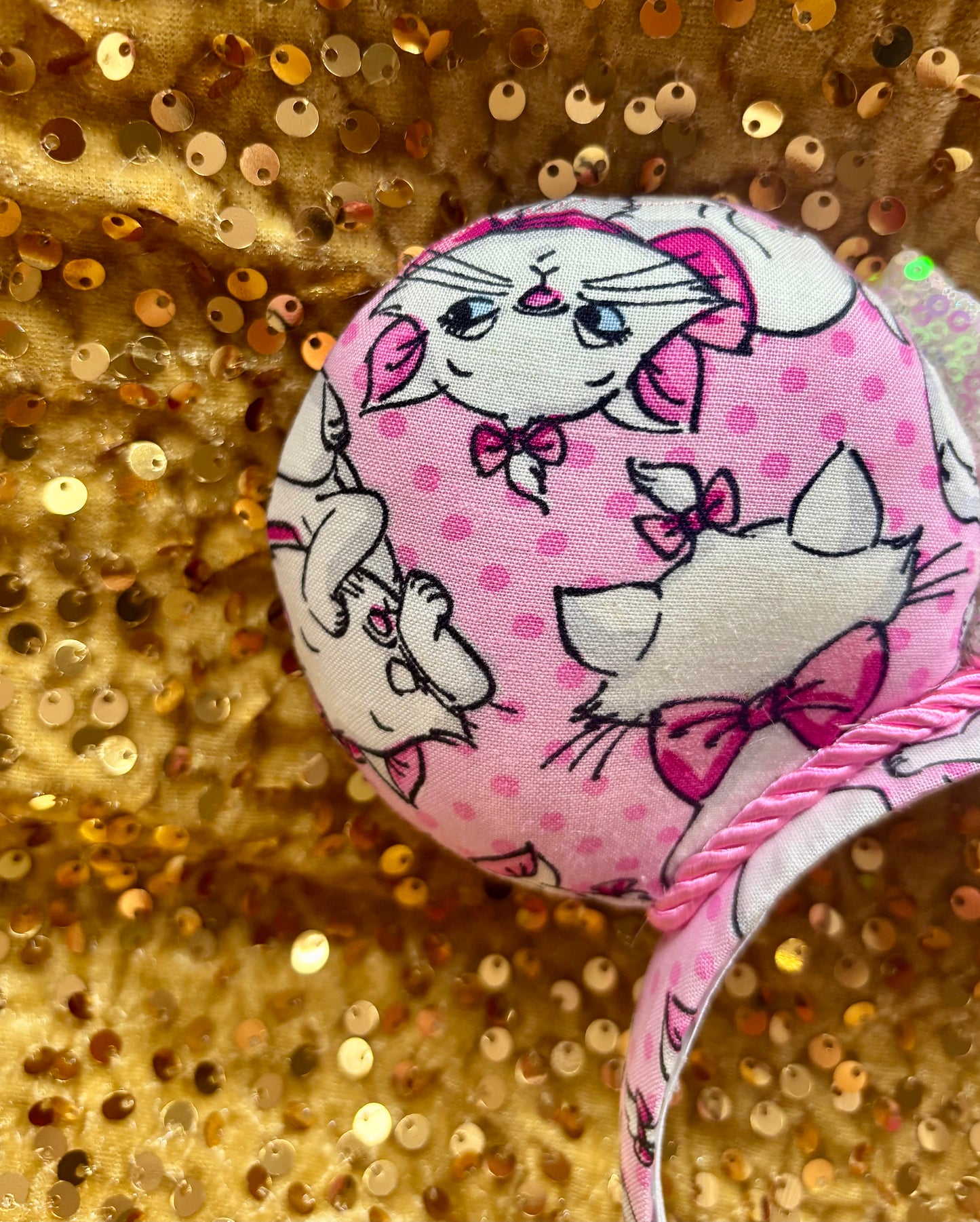 Pink mouse ear headband with white bow shown on a gold glitter background