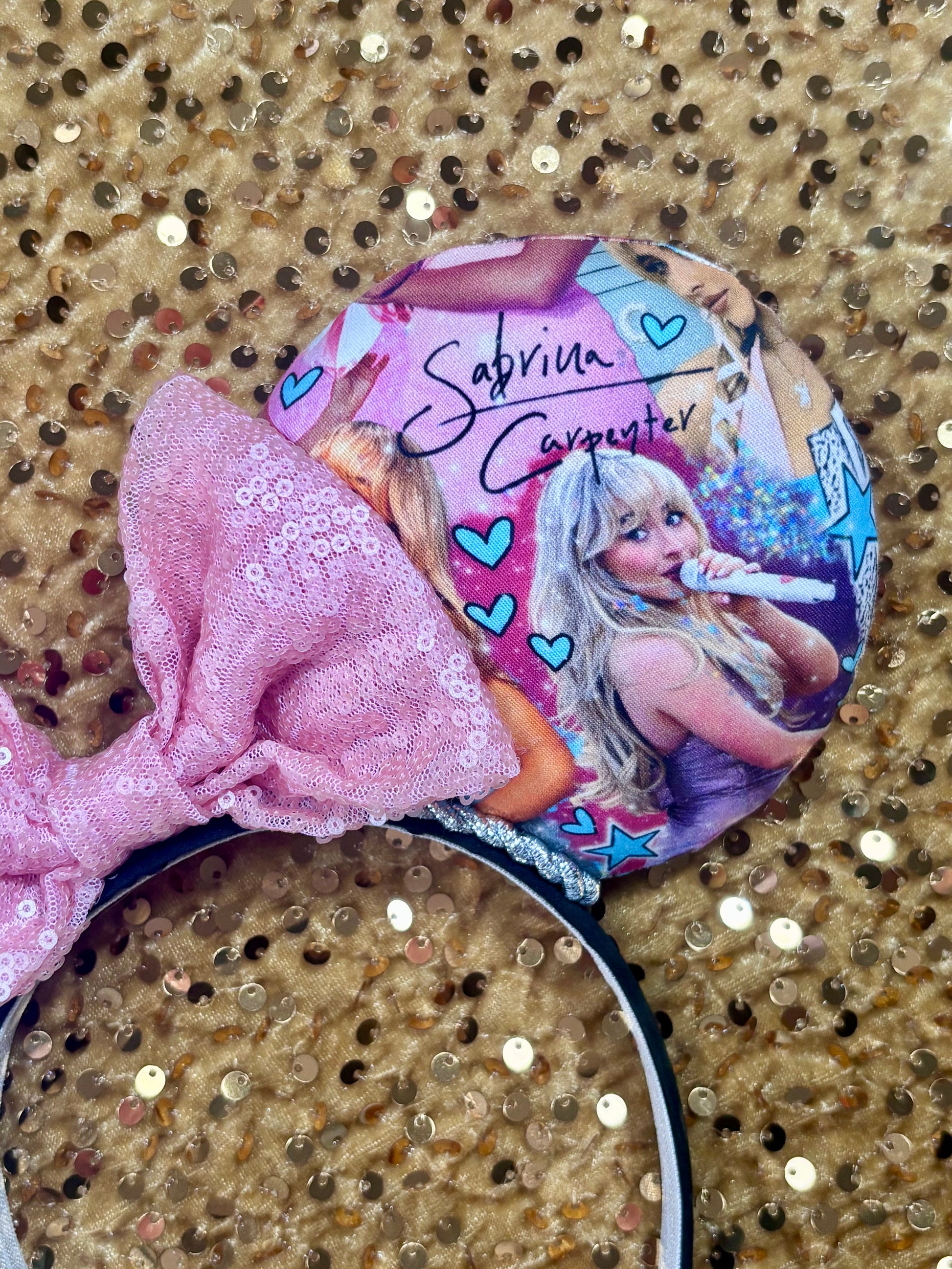 Headband with pink bow and 'Sabrina Carpenter' design on a glittery background