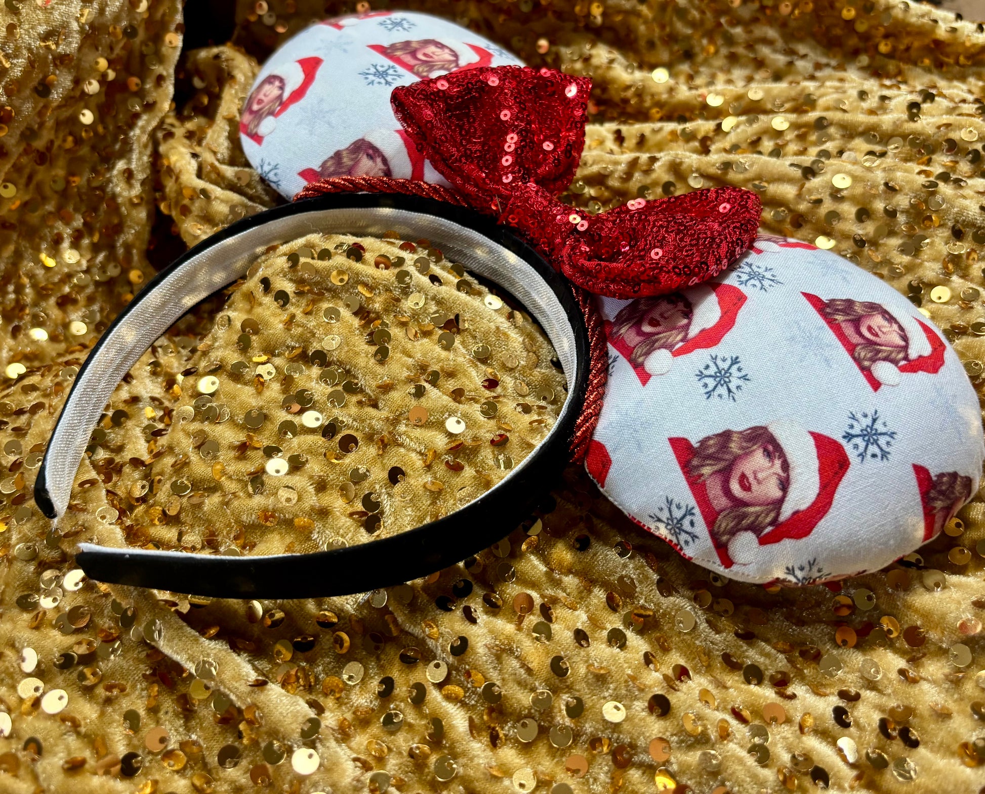 Decorative headband with red sequin bow and fabric ears on a gold sequin background