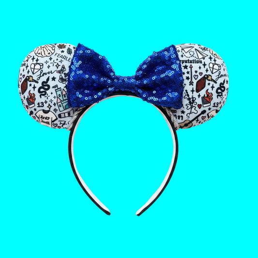 Handmade and ready to ship Tay Doodles mouse ears with drawings and titles of albums on fabric on a black universal headband, with silver trim and a blue sequin bow.