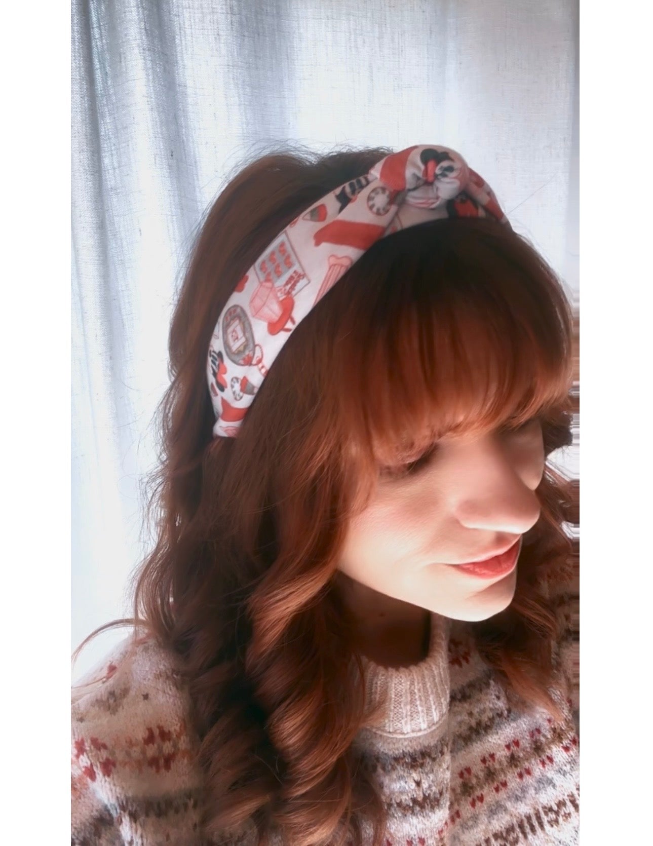 Model Tam wearing a patterned Stocking Stuffers headband with a soft-focus background.