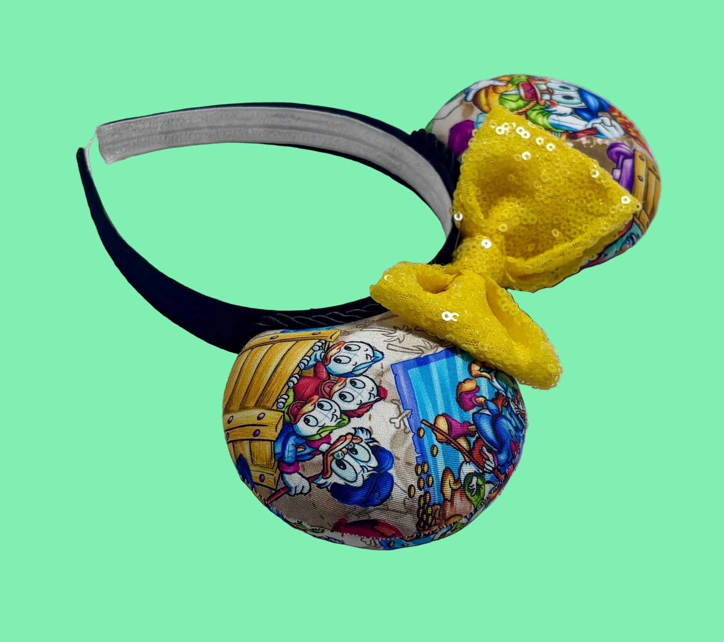 Colorful mouse ears with DuckTales Inspired fabric with a Yellow Sequin bow. Angled view of headband to show the ear and headband.