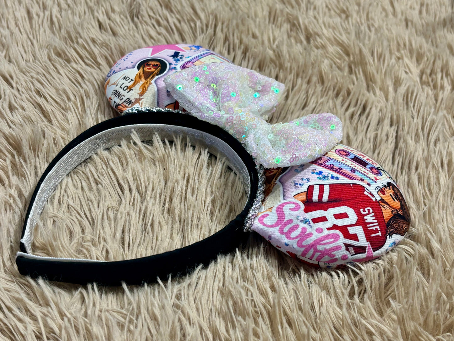 An ear headband with a large iridescent bow and custom printed ears featuring retro cassette graphics, a pink star, and a portrait of singer.