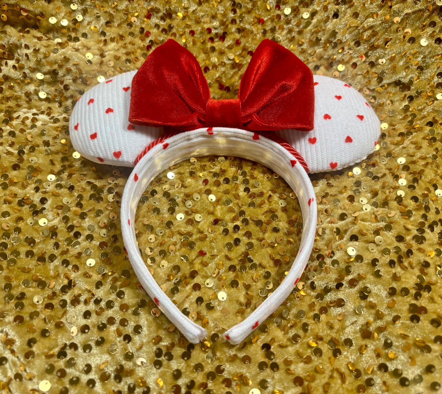 Handmade and ready to ship, Be Mine Custom Ears. Fabric is on ears front and back with red twisted trim along the inner ears and a big puffy plush red bow. The Headband is universal sized and has the same white fabric with hearts pattern on it.
