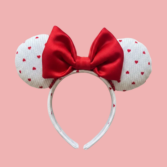 Handmade and ready to ship, Be Mine Custom Ears. Fabric is on ears front and back with red twisted trim along the inner ears and a big puffy plush red bow. The Headband is universal sized and has the same white fabric with hearts pattern on it.