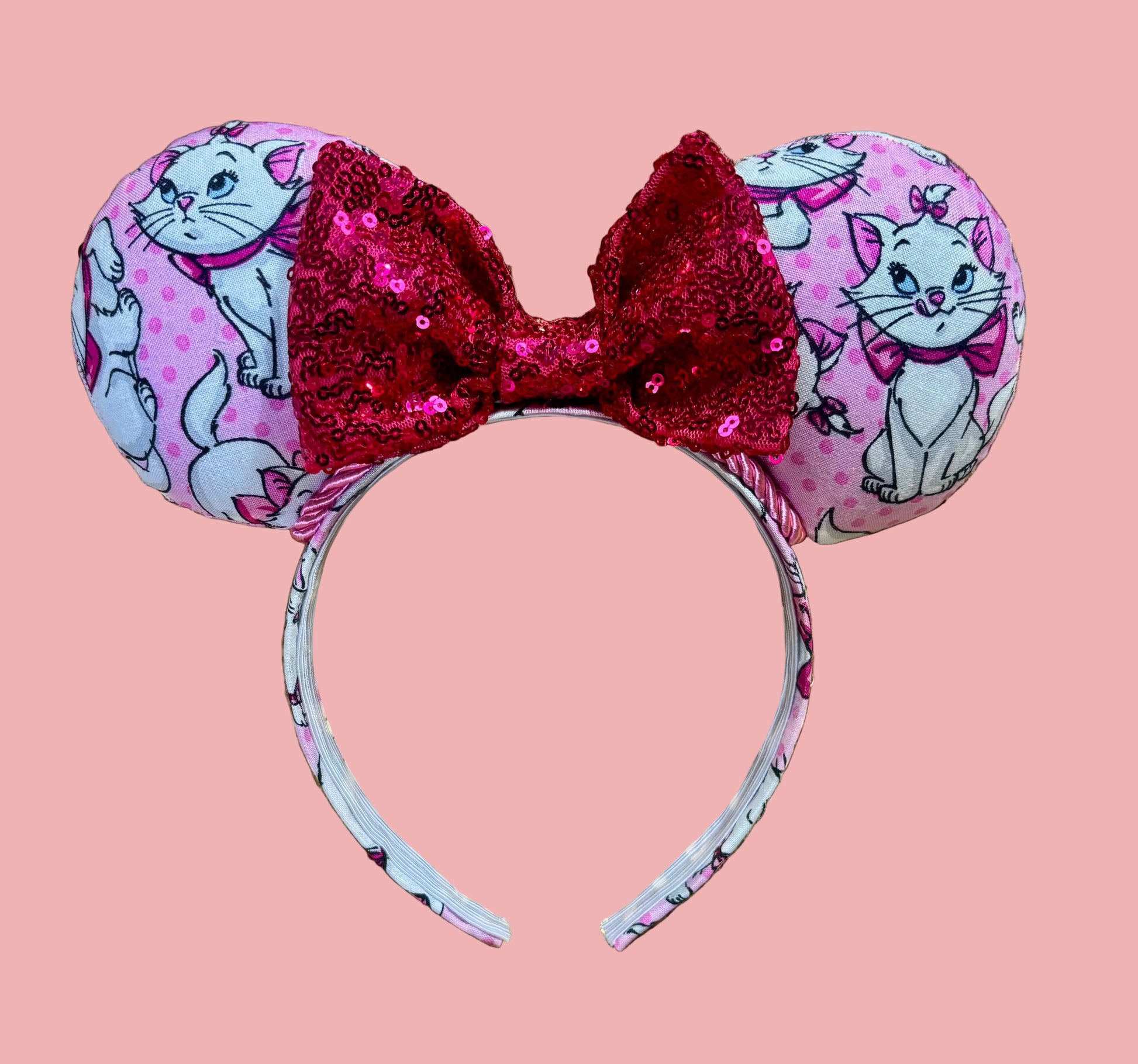 Handmade and ready to ship Marie Inspired Mouse ears with images of her on the front and back of mouse ears shown with a Hot Pink sequin bow. The headband has a matching Marie poly cotton fabric and is a universal sized headband. 