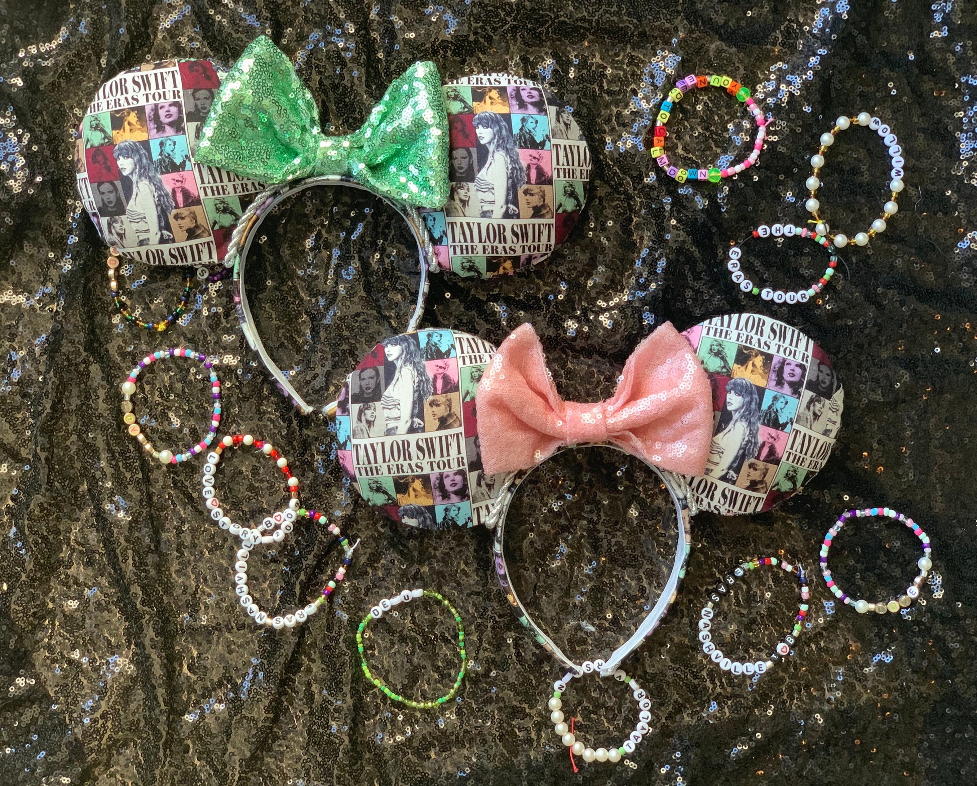 Two custom headbands with a collage print pattern and bows (one green glitter, one pink glitter) surrounded by various beaded bracelets on a dark surface.
