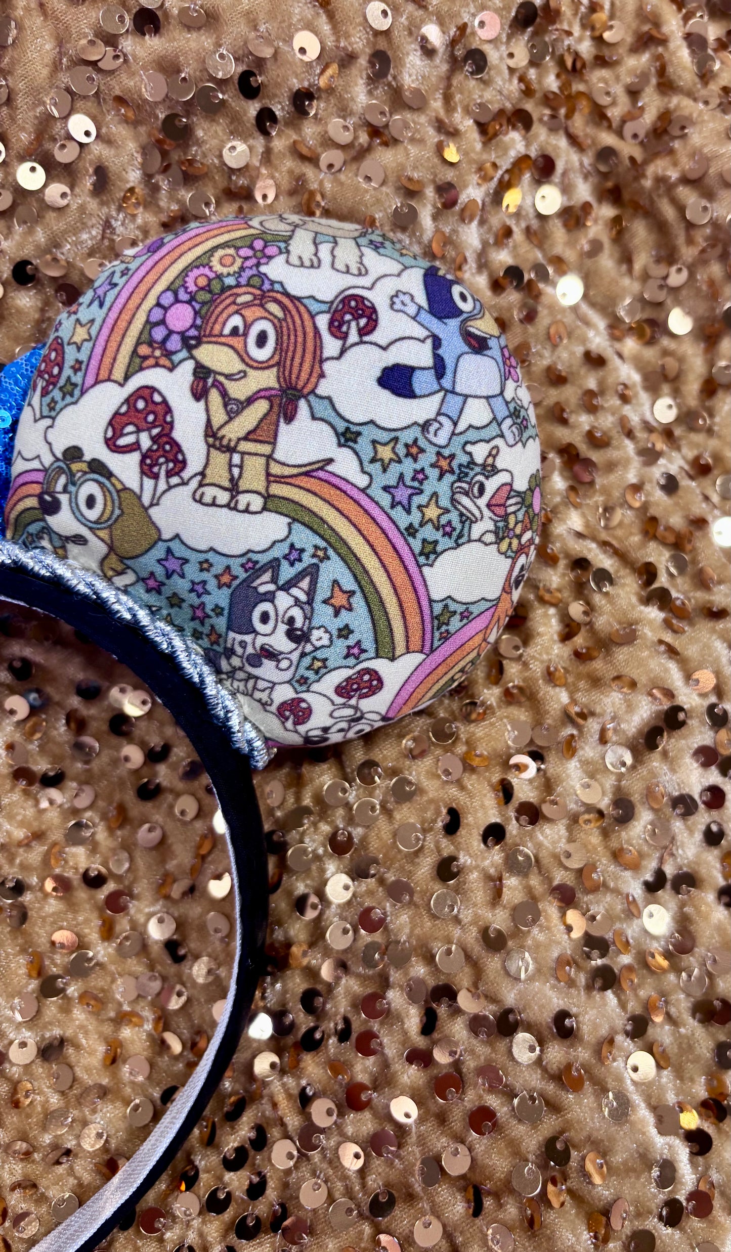 Mouse ears with a blue bow and colorful floral pattern with Bluey and friends on a white background