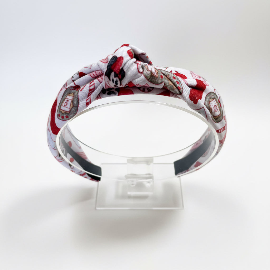 Headband with red and white pattern on a clear stand against a white background.