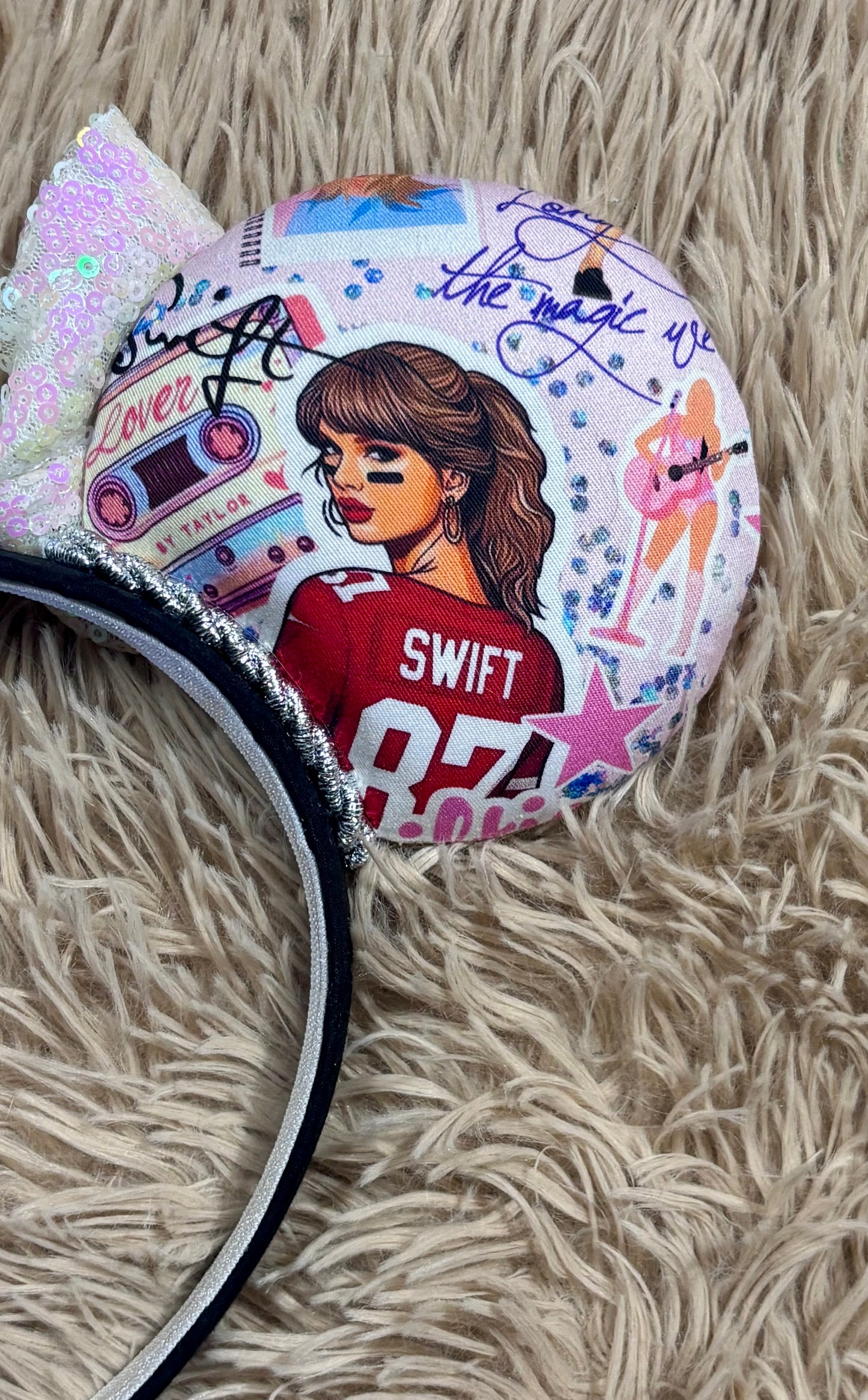 An ear headband with a large iridescent bow and custom printed ears featuring retro cassette graphics, a pink star, and a portrait of singer.