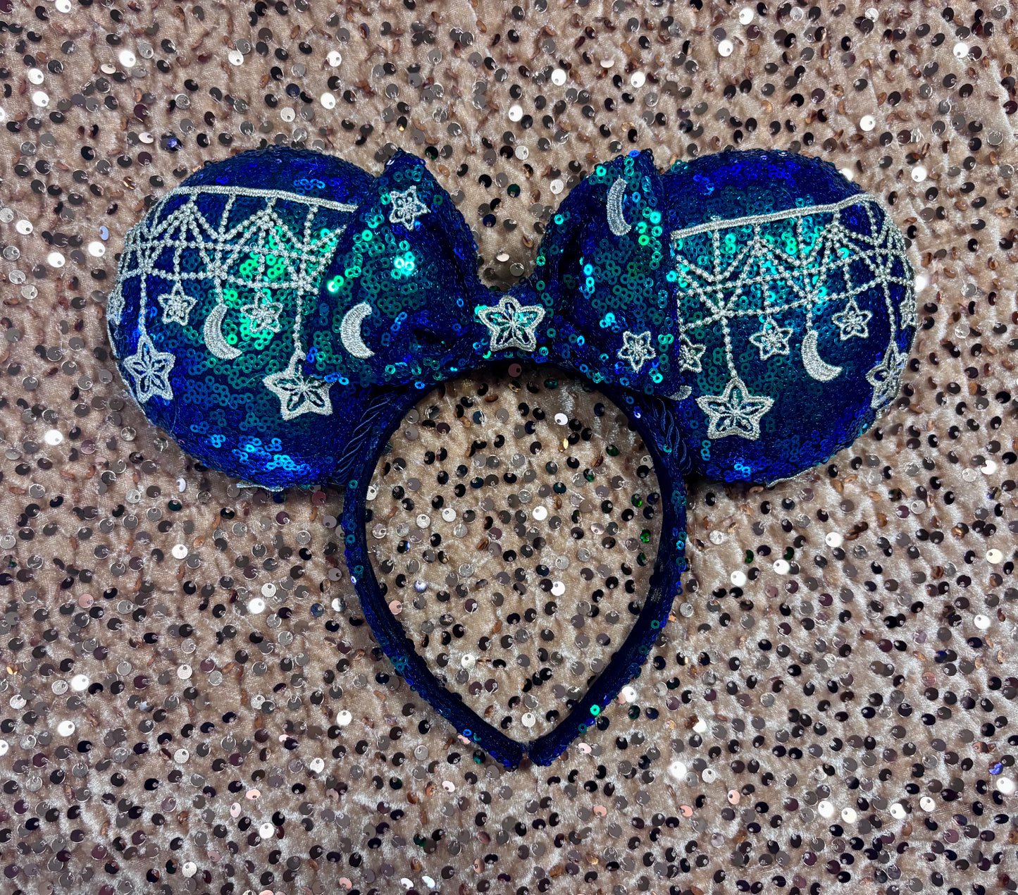 Mouse Ear headband that is a Handmade Iridescent blue and green sequins with gold sun, moon and stars attached to them. bow with star and moon patterns.