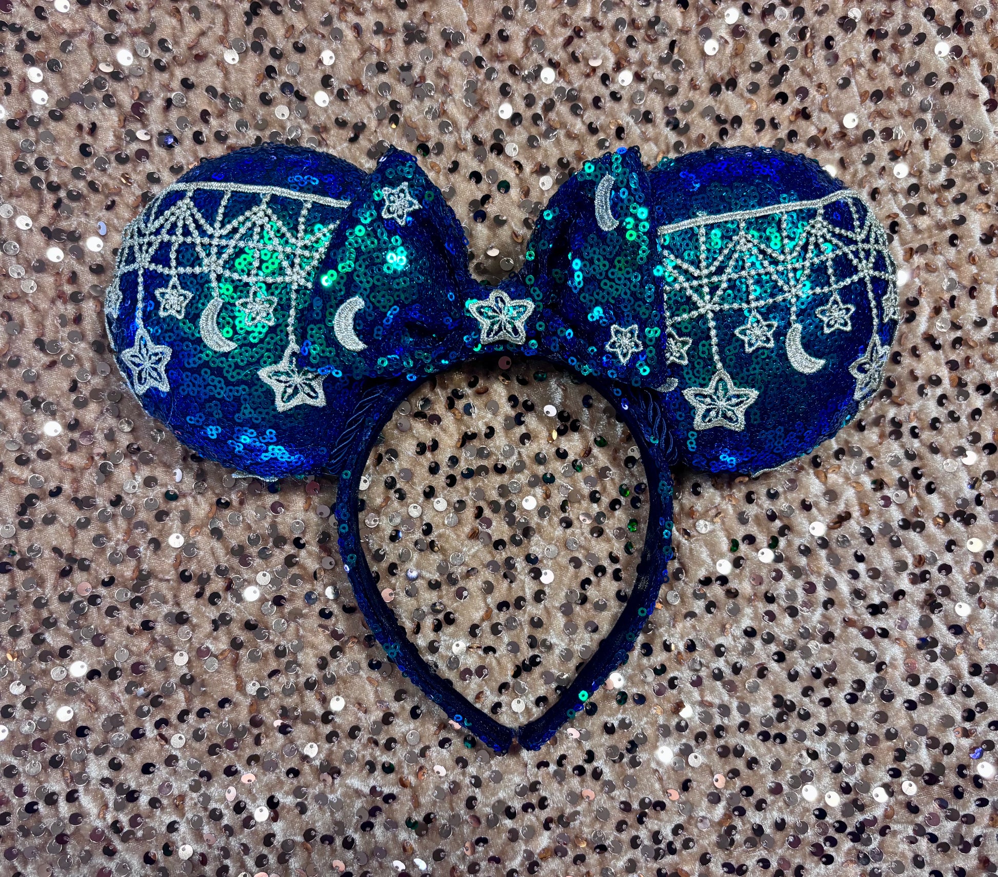 Mouse Ear headband that is a Handmade Iridescent blue and green sequins with gold sun, moon and stars attached to them. bow with star and moon patterns.