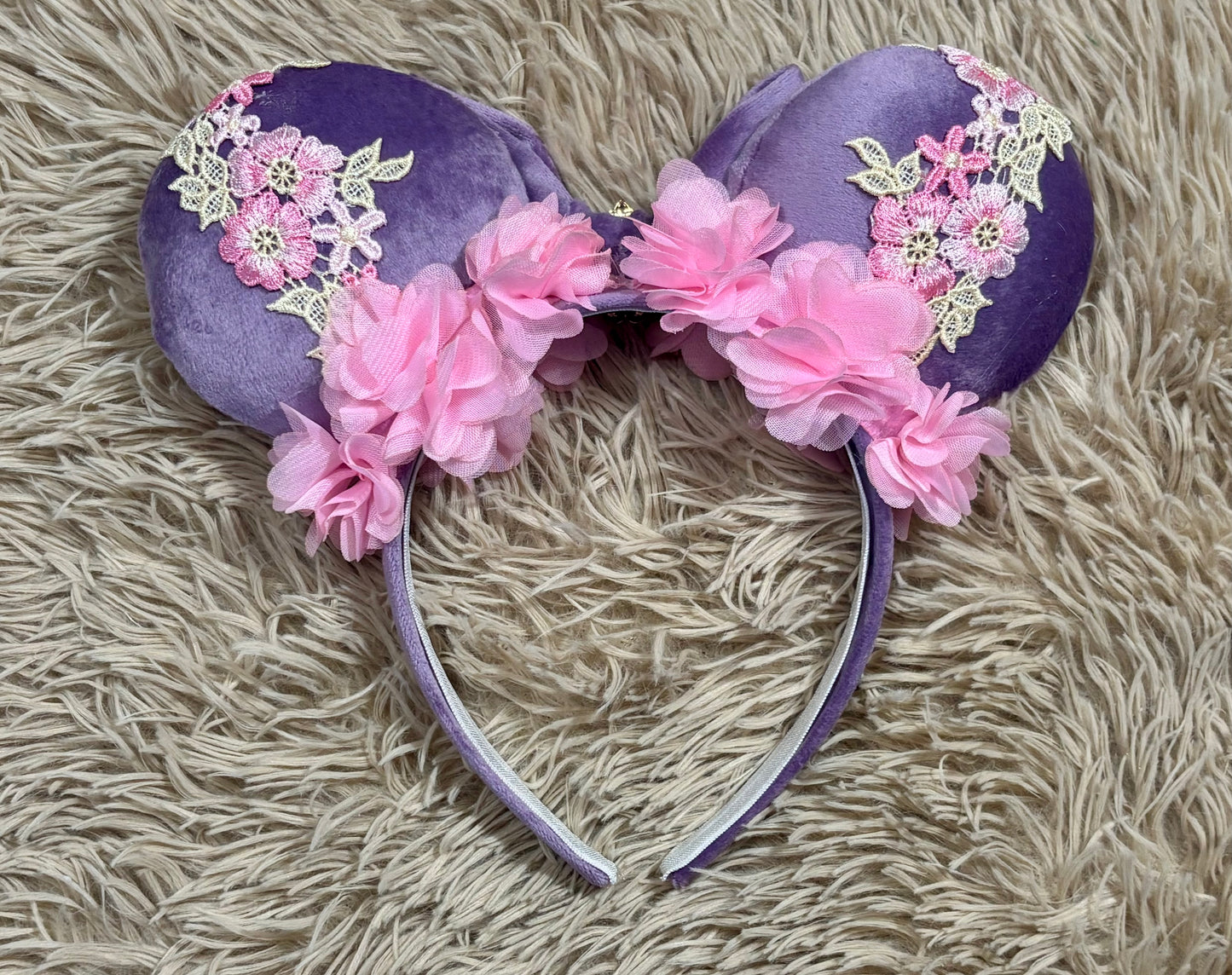 Back view of purple and pink fabric mouse ears headband with a large velvet bow, floral lace appliques, and a purple gem accent.