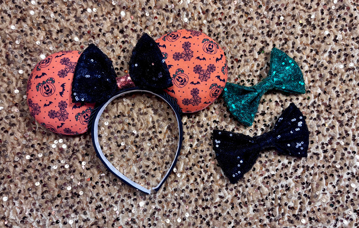 Halloween mouse ears with the fabric on both the front and back. It's orange with bats, mouse shaped pumpkins and spider webs. The headband is black universal sized and fits most. The set has a black with orange middle sequin bow. Item is shown on a gold sequin background. shown with a green sequin bow and an all-black sequin bow in case you prefer a different color. Just write a note in your order if so. 