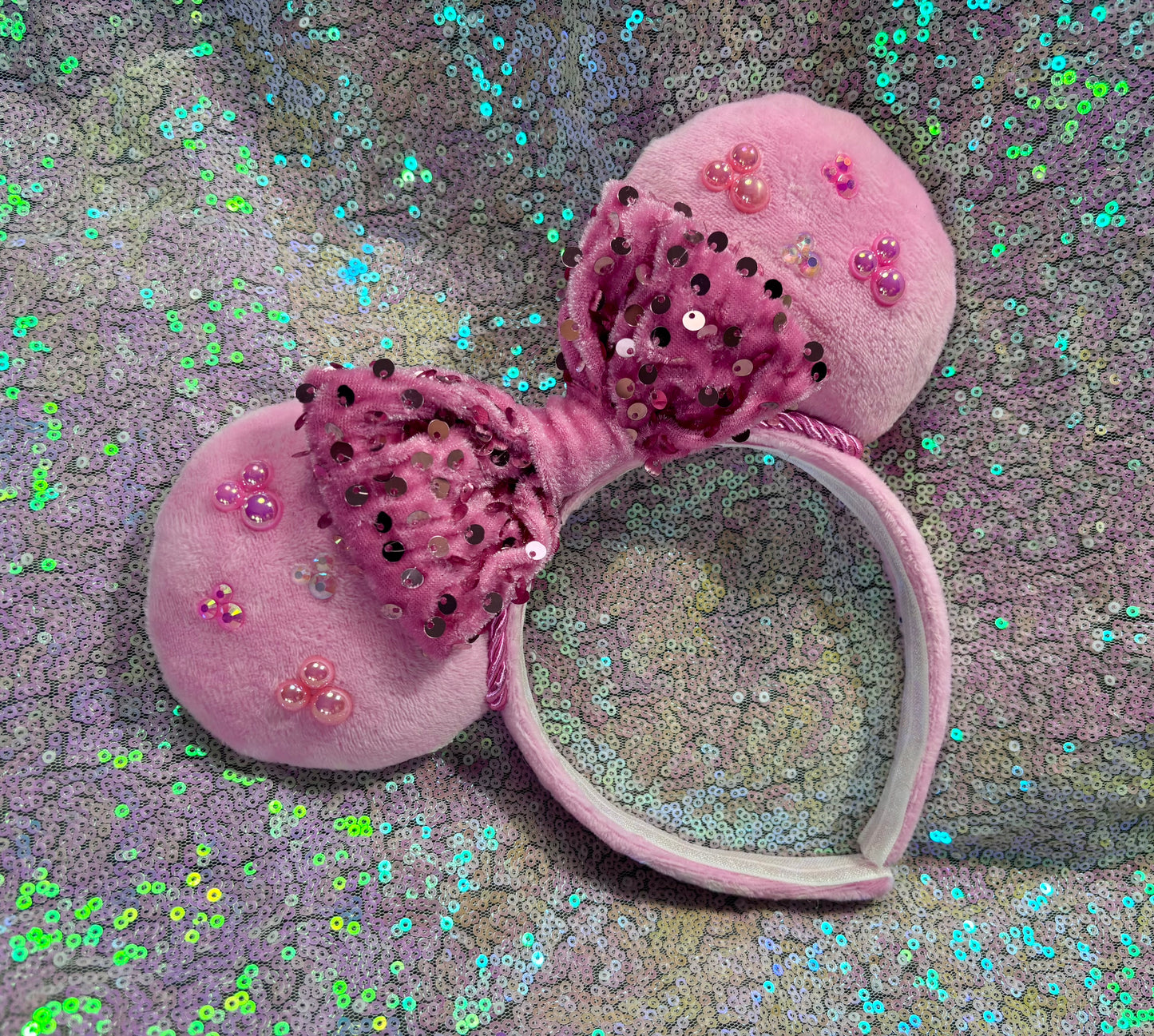 Pink Minnie Mouse ears with sequins on a glittery background