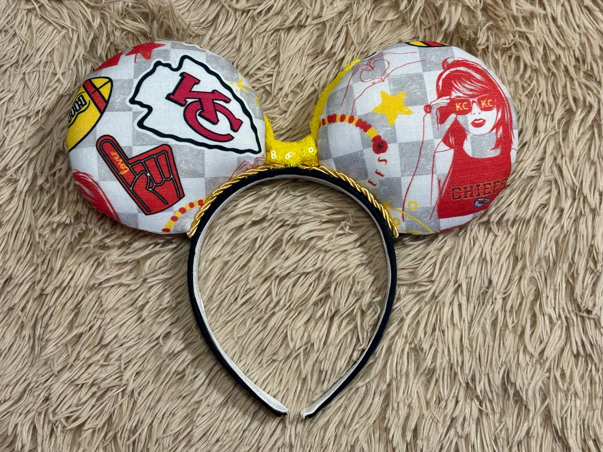 Back view of mouse ears. An ear headband featuring a bright yellow sequined bow. The set has TS and Chiefs images on it. Set on a universal sized headband.