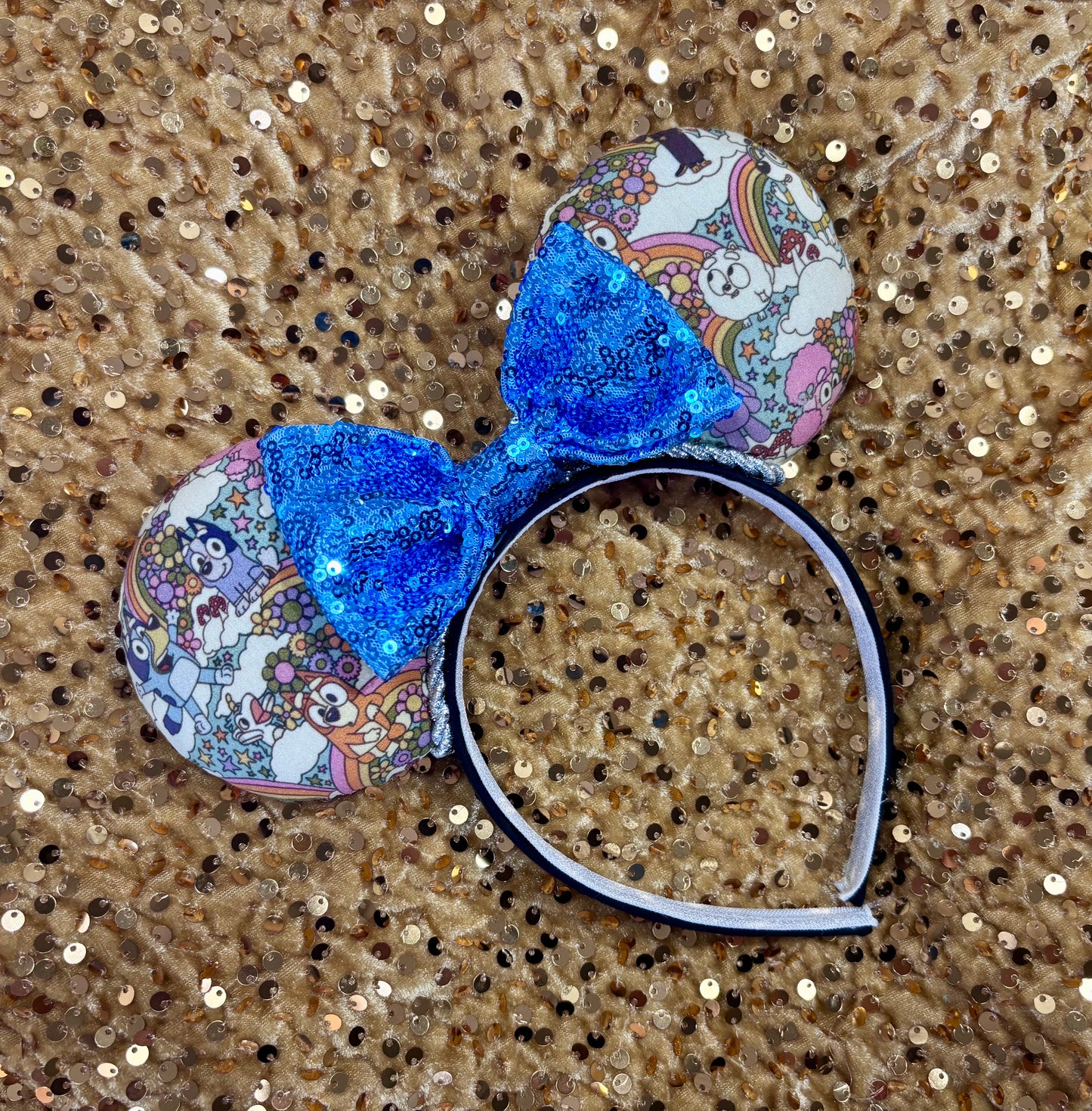 Mouse ears with a blue bow and colorful floral pattern with Bluey and friends on a white background